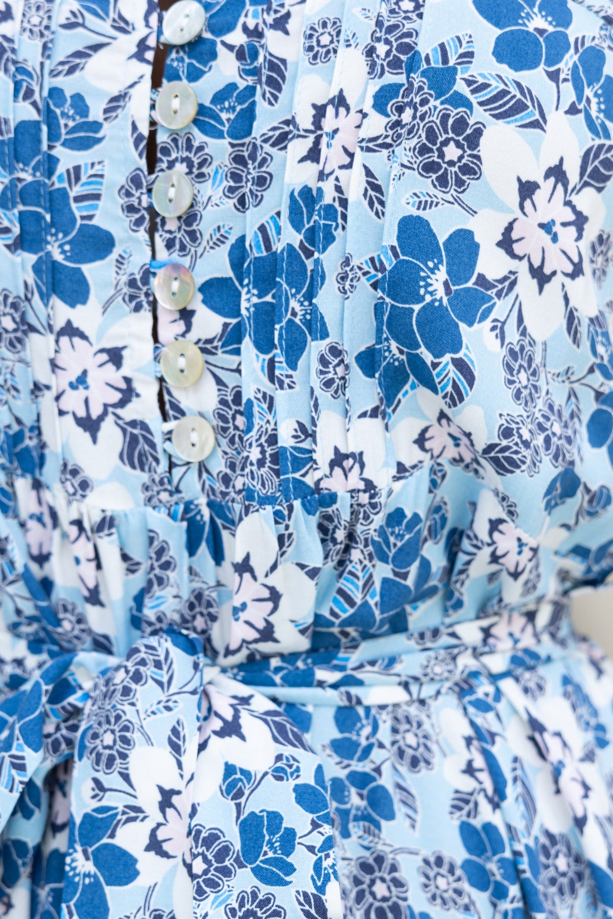 Close-up of Sevila Midi Dress featuring floral print, adjustable straps, button-up front, and removable tie detail.