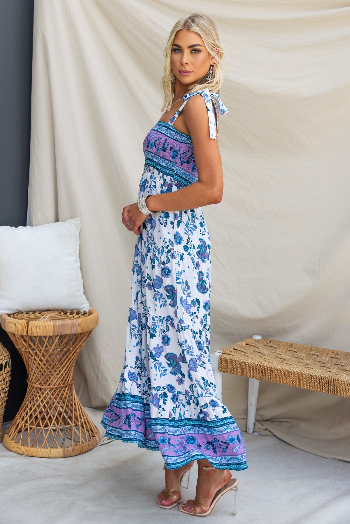 Adios Maxi Dress featuring adjustable tie straps and elastic bodice in a blue floral print, styled with trendy heels.