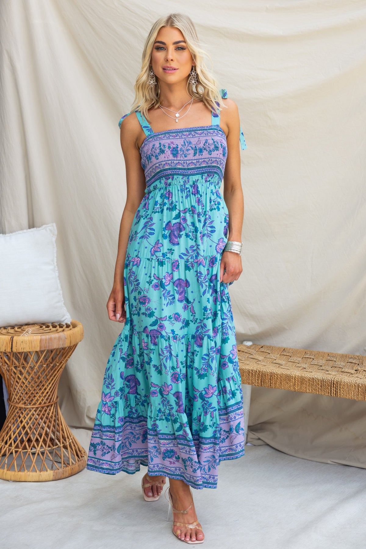 Model wearing Adios Maxi Dress with floral print, adjustable tie straps, and elastic bodice, styled in a natural setting.