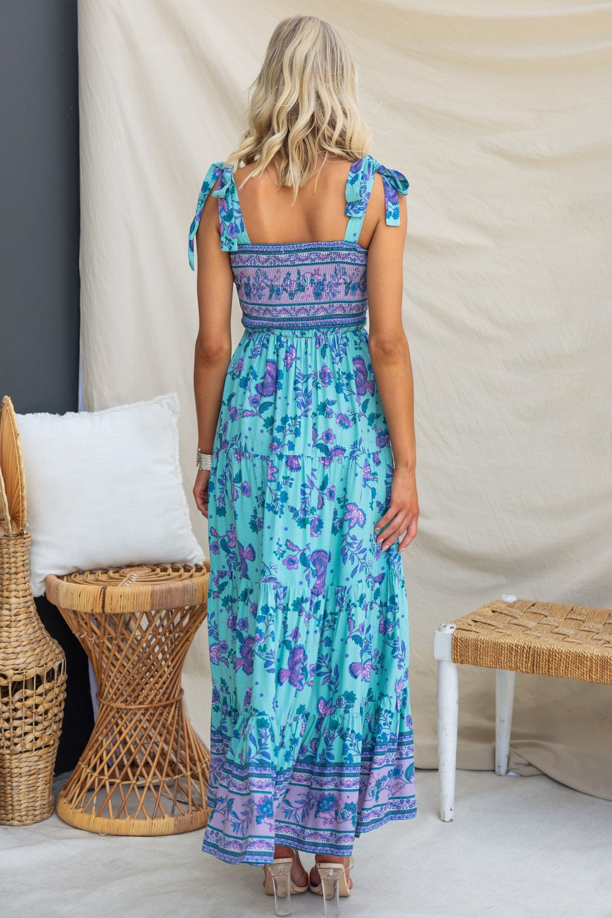 Back view of a woman wearing the Adios Maxi Dress with adjustable tie straps, featuring a floral pattern and elastic bodice.