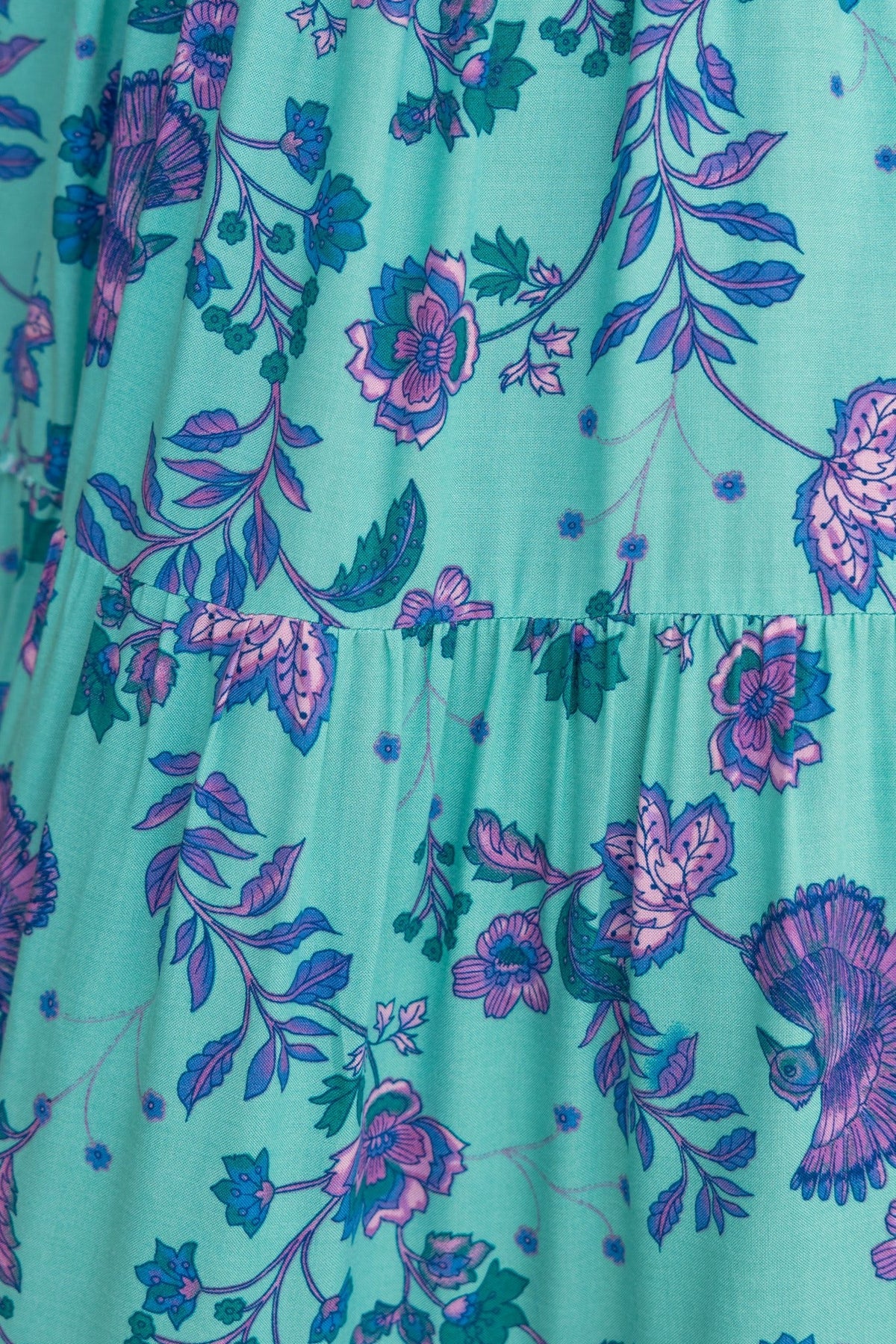 Close-up of Adios Maxi Dress fabric featuring vibrant blue and pink floral patterns on a teal background.
