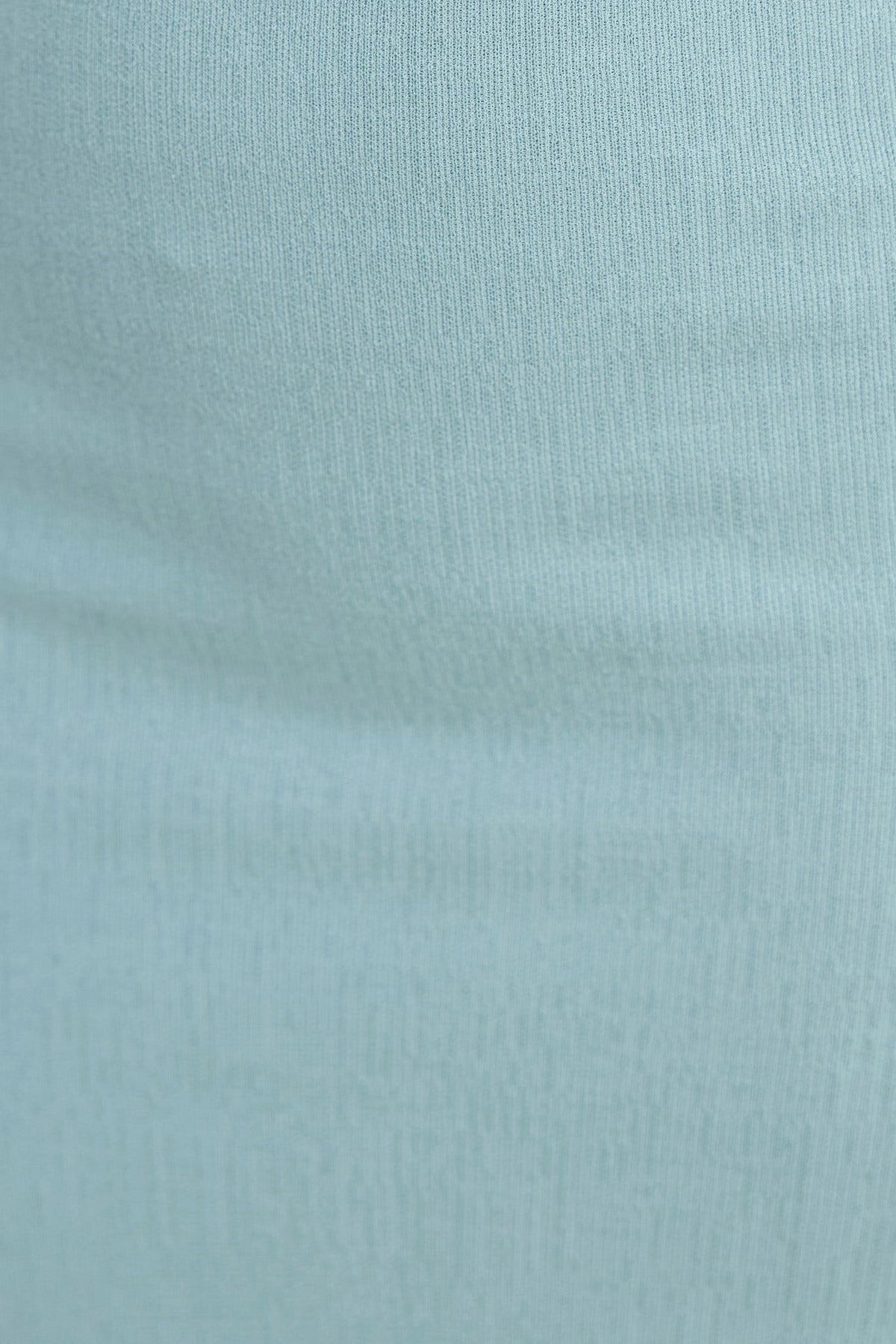 Close-up of light blue textured fabric showcasing soft stretch and smooth surface for Lanza Top.