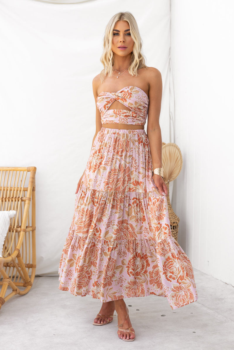 Model wearing an enchanting maxi skirt with floral print and a strapless top, showcasing a mid-high waist fit in a stylish setting.