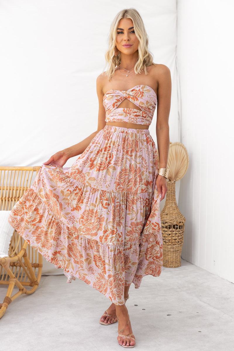 Model wearing an enchanting strapless floral dress with twist detail and flowing skirt in a bright, airy setting.