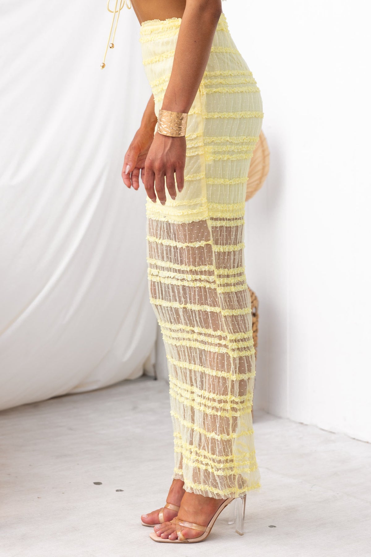 Model wearing a yellow Naysha Maxi Skirt, featuring a mid-high waist and mesh overlay, styled with clear heels.