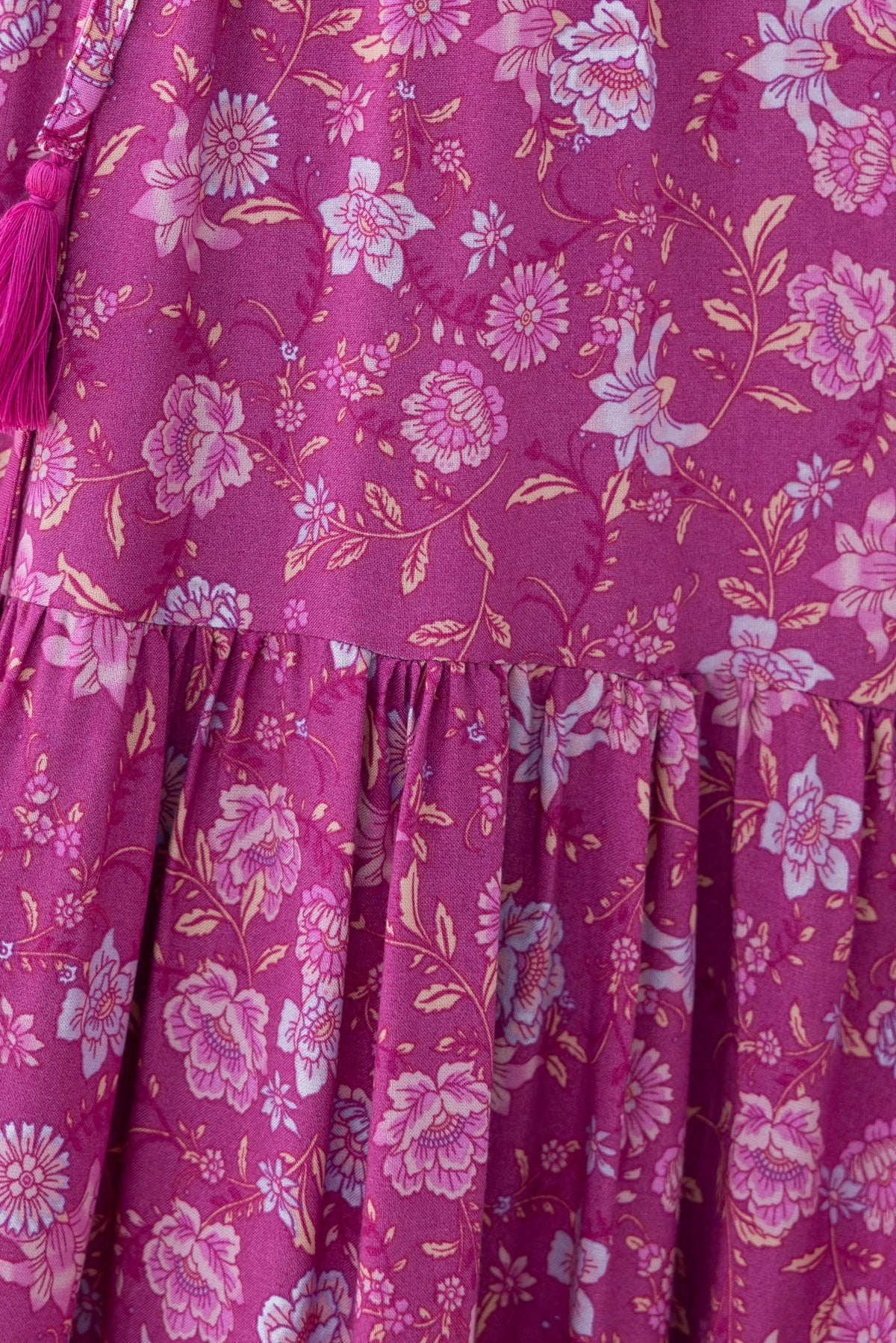Close-up of Sadelle Midi Dress featuring vibrant pink floral pattern and ruffled hem detail.