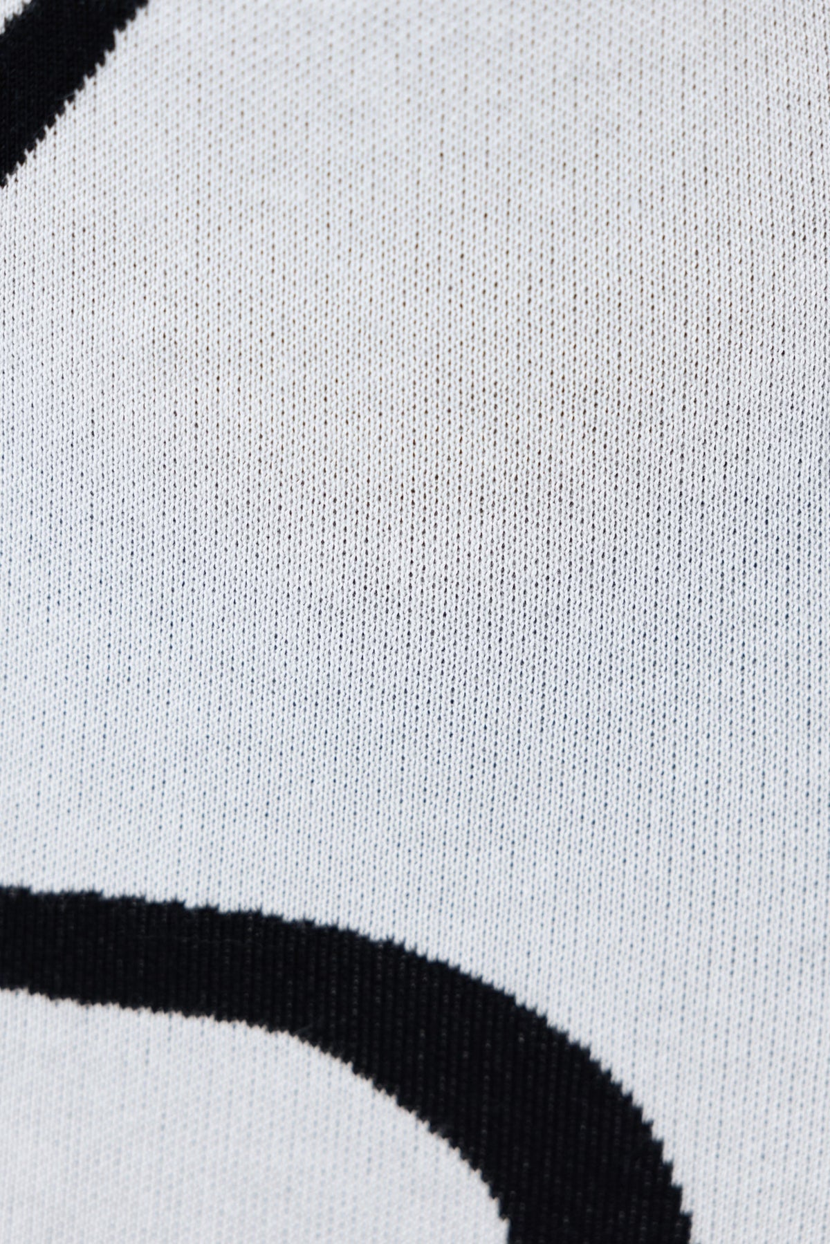 Close-up of knit fabric showing stretch and texture, featuring black and white design, perfect for casual wear.