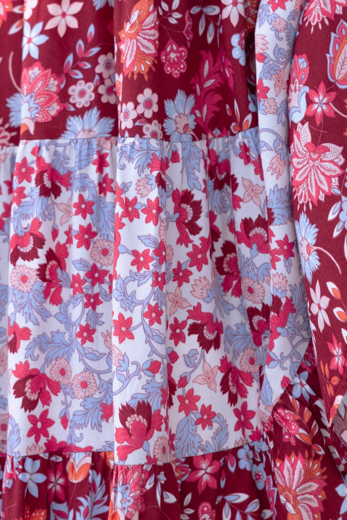 Close-up of Aryana Midi Dress featuring floral prints in red and blue with tiered design and adjustable straps.