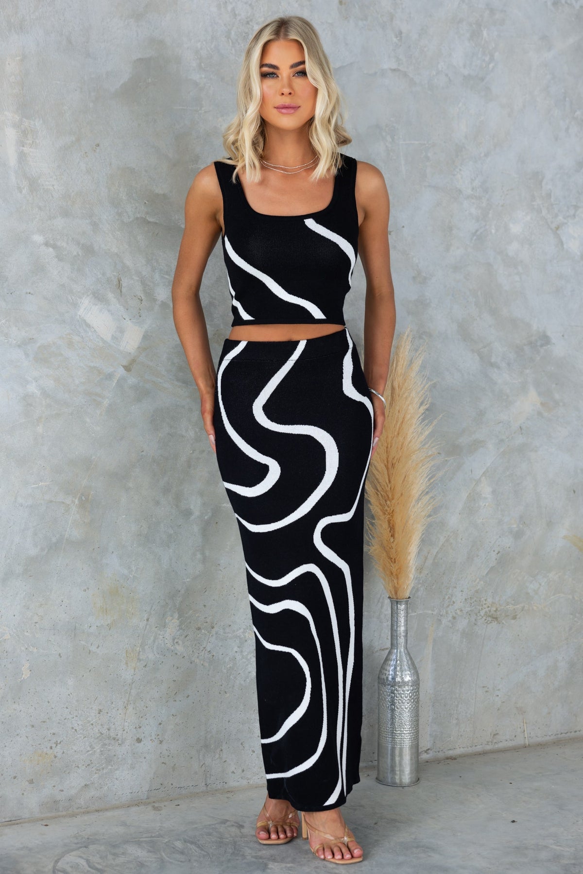 Model in black and white patterned crop top and fitted maxi skirt, showcasing a stylish summer outfit.