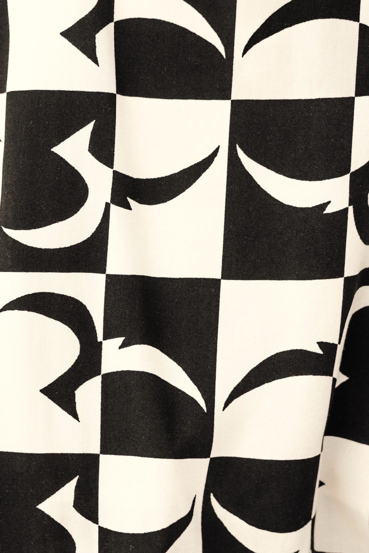 Black and white patterned fabric featuring abstract shapes in checkered design, ideal for fashion products.