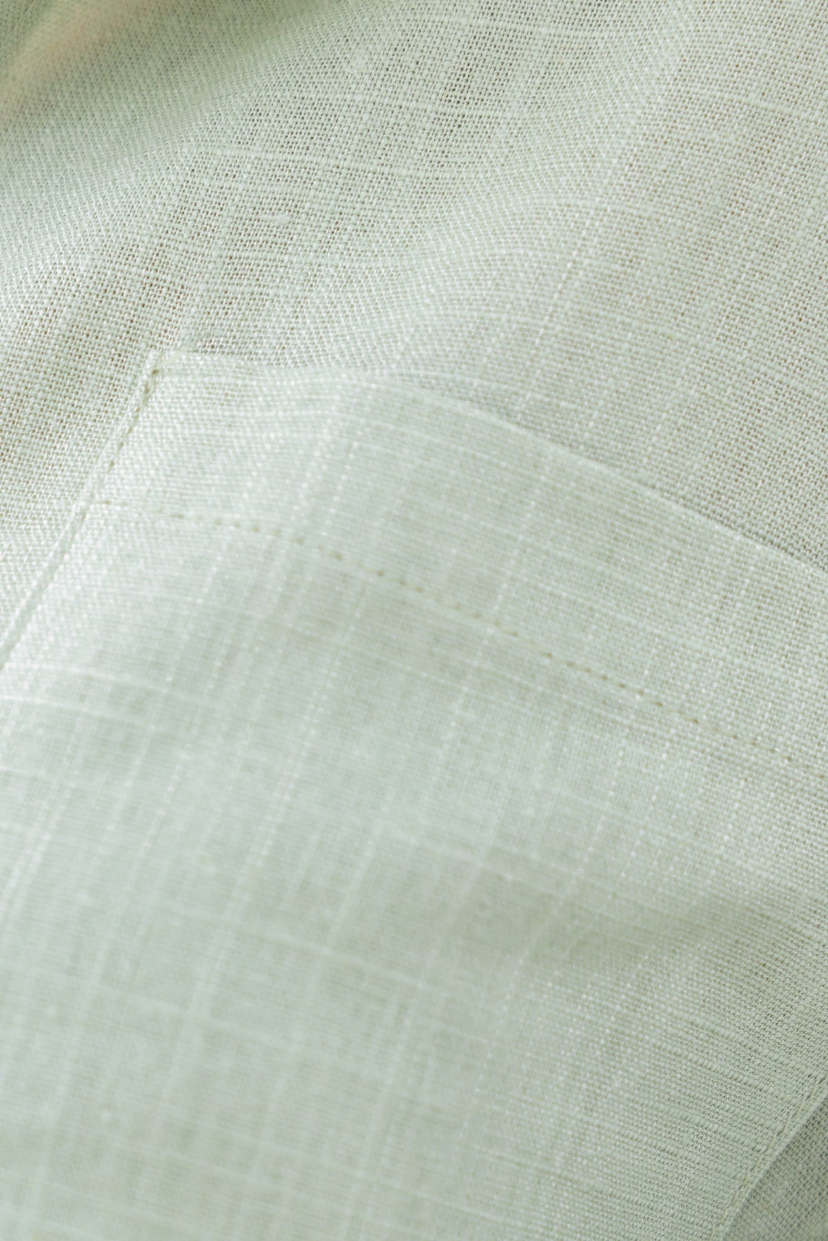 Close-up of soft green fabric showcasing a textured linen look with a pocket detail.