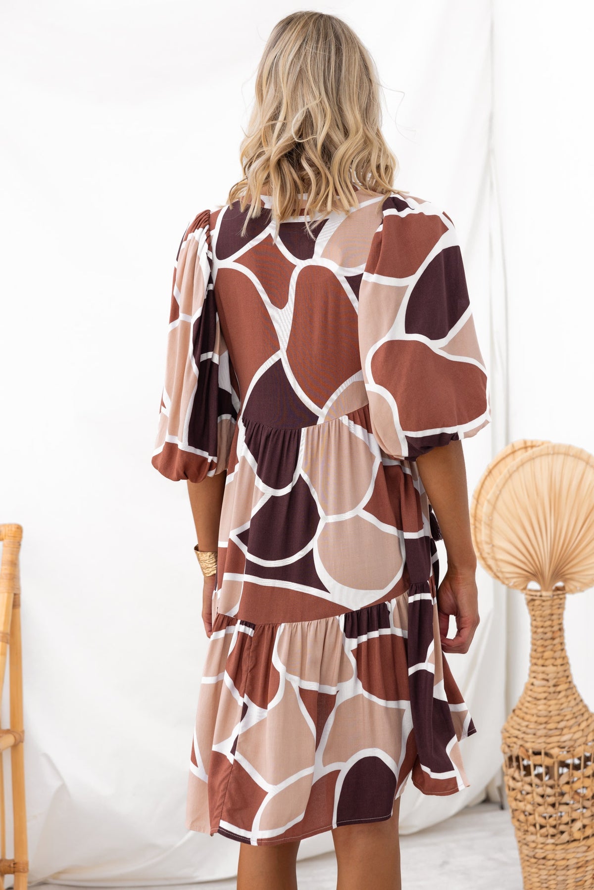 Back view of Alisti Dress featuring a V-neckline and tie detail, showcasing its unique brown abstract pattern.
