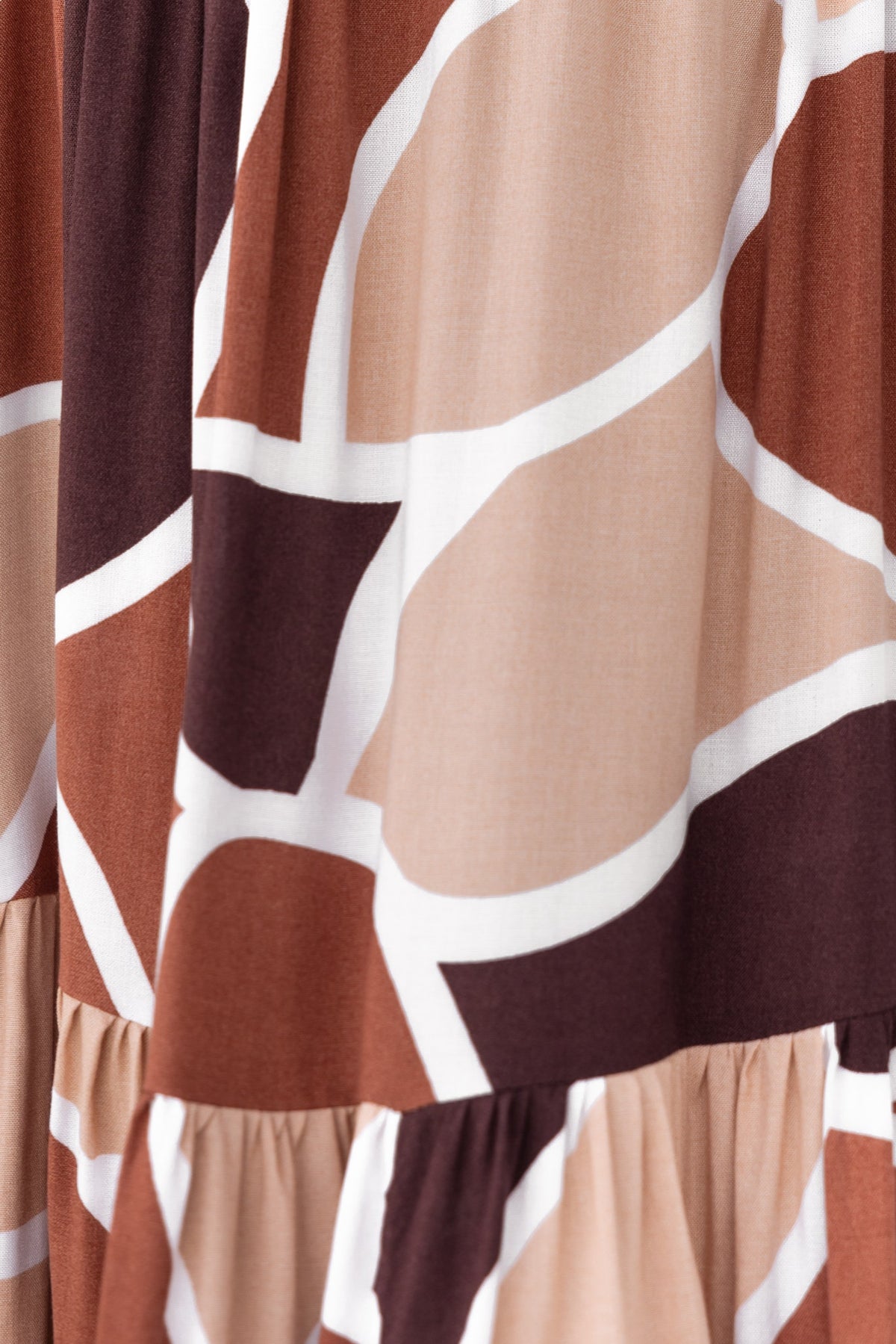 Close-up of Maito Shirt featuring a stylish abstract pattern in warm tones of brown, beige, and cream.