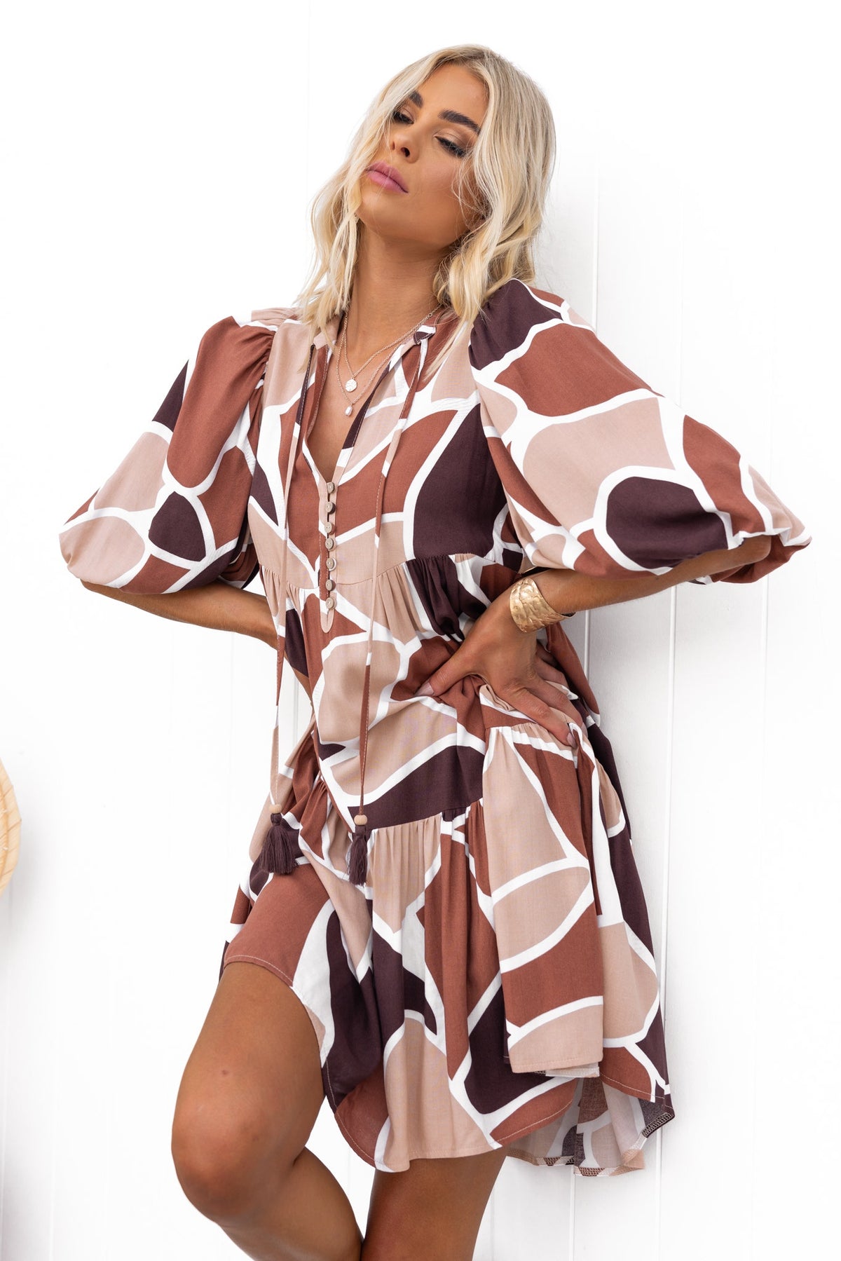 Alisti Dress featuring a V-neckline, tie detail, and relaxed fit in a stylish brown and cream pattern.