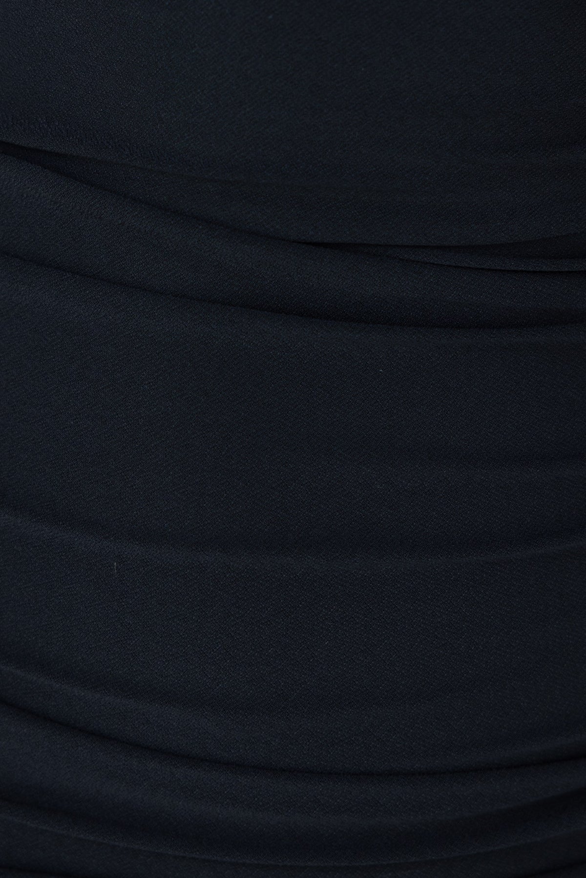 Close-up of black dress fabric featuring ruching details, showcasing soft stretch material.