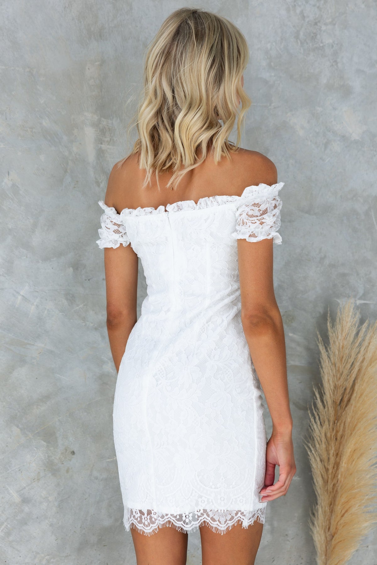 Back view of a white lace Jadiel dress with off-the-shoulder neckline, showcasing the fitted silhouette and lace details.
