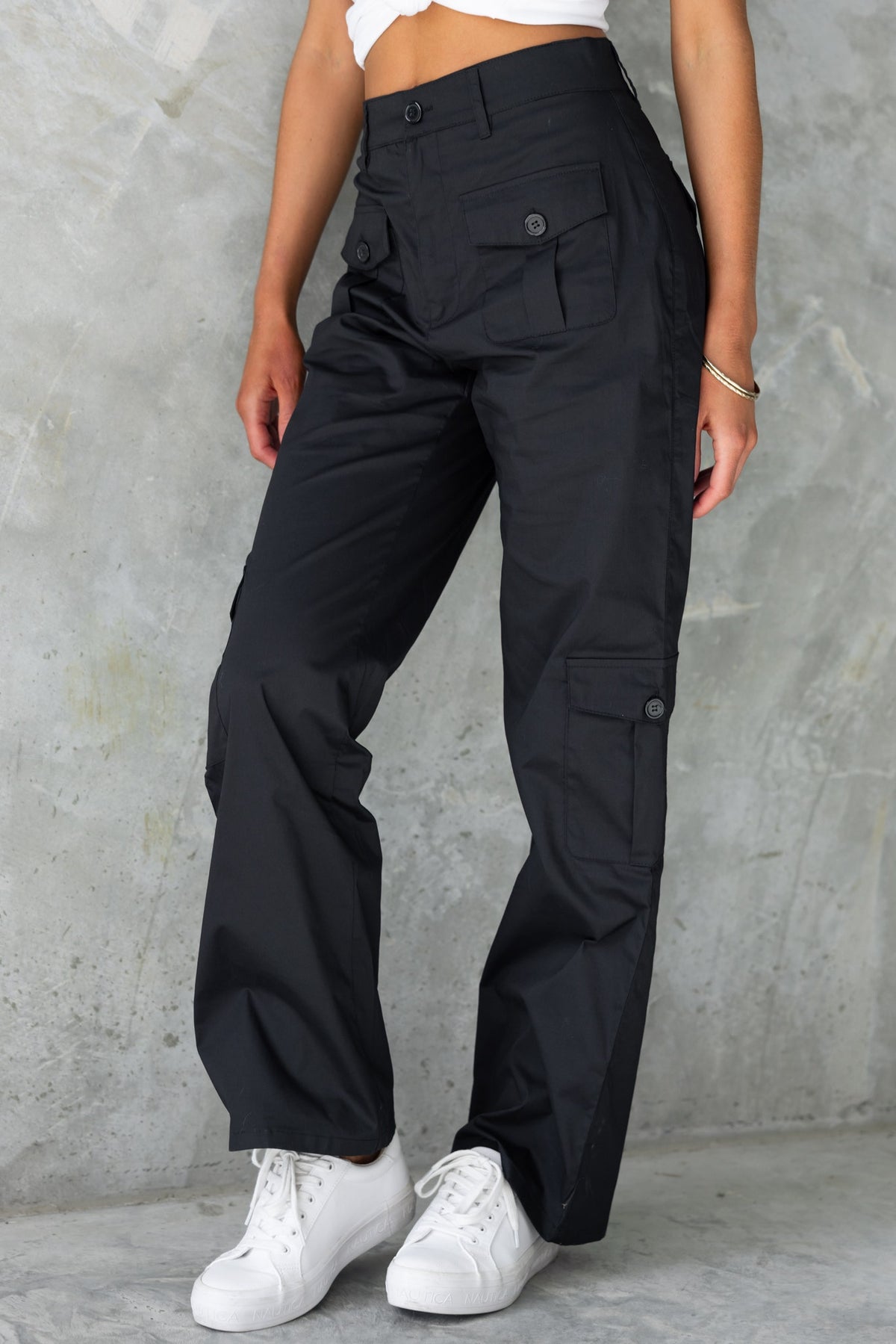 Black high-waisted cargo pants with pockets, styled with white sneakers, perfect for casual wear.