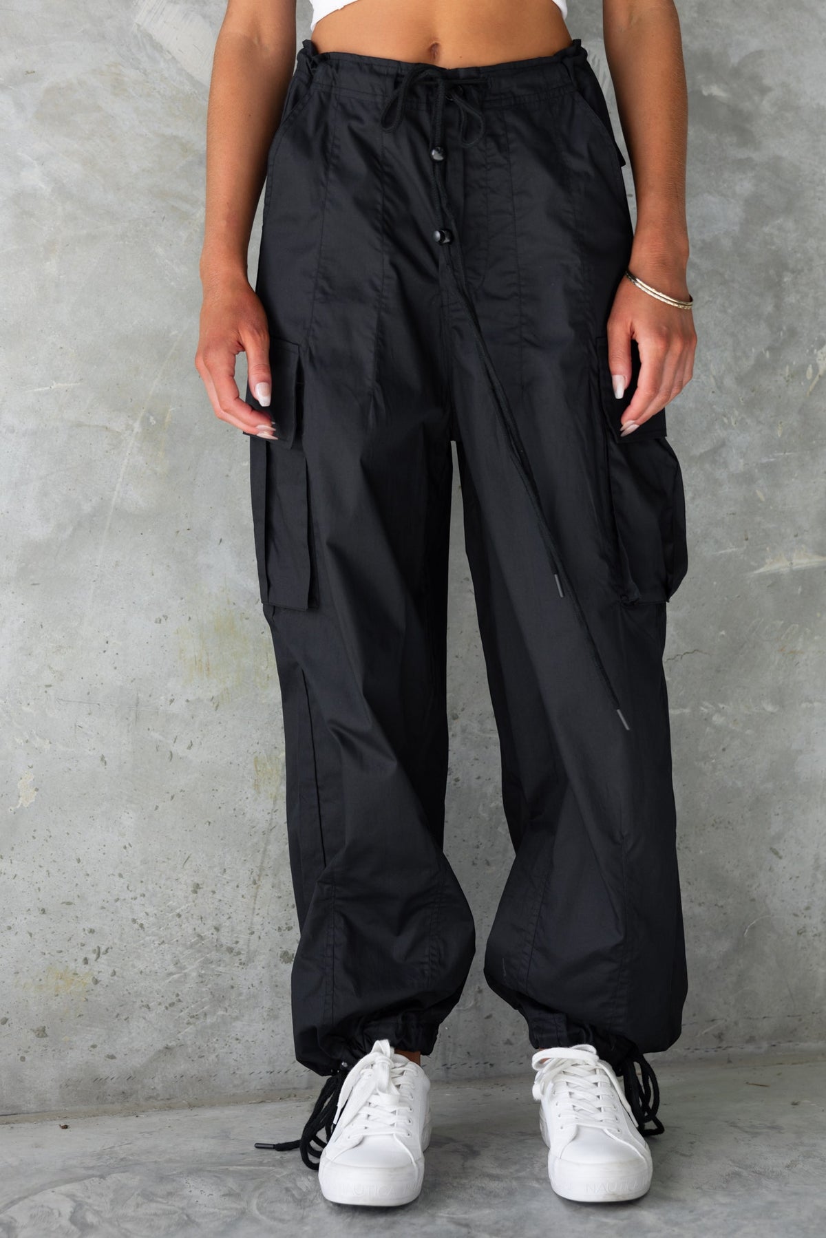 Model wearing Conrad Cargo Pants in black, featuring a high-mid waist, drawstring, and wide legs.
