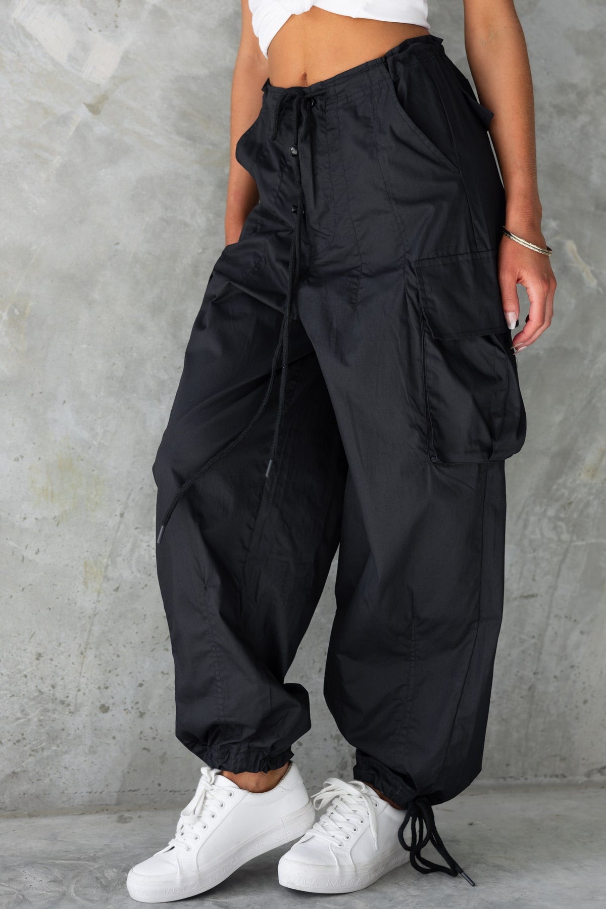 Conrad Cargo Pants in black with drawstring waistband and wide legs, styled with a cropped top and white sneakers.