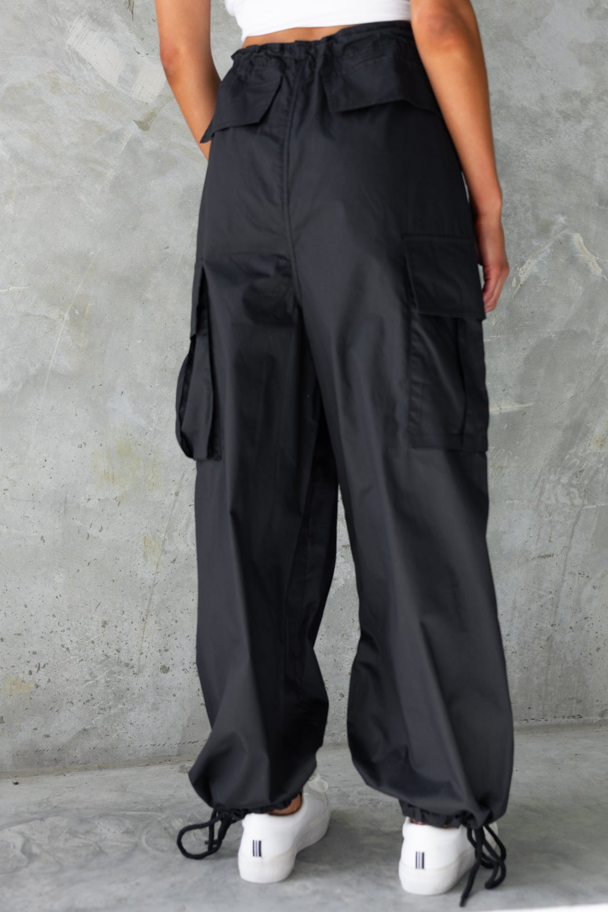 Back view of black Conrad Cargo Pants featuring wide legs, drawstrings, and multiple pockets.