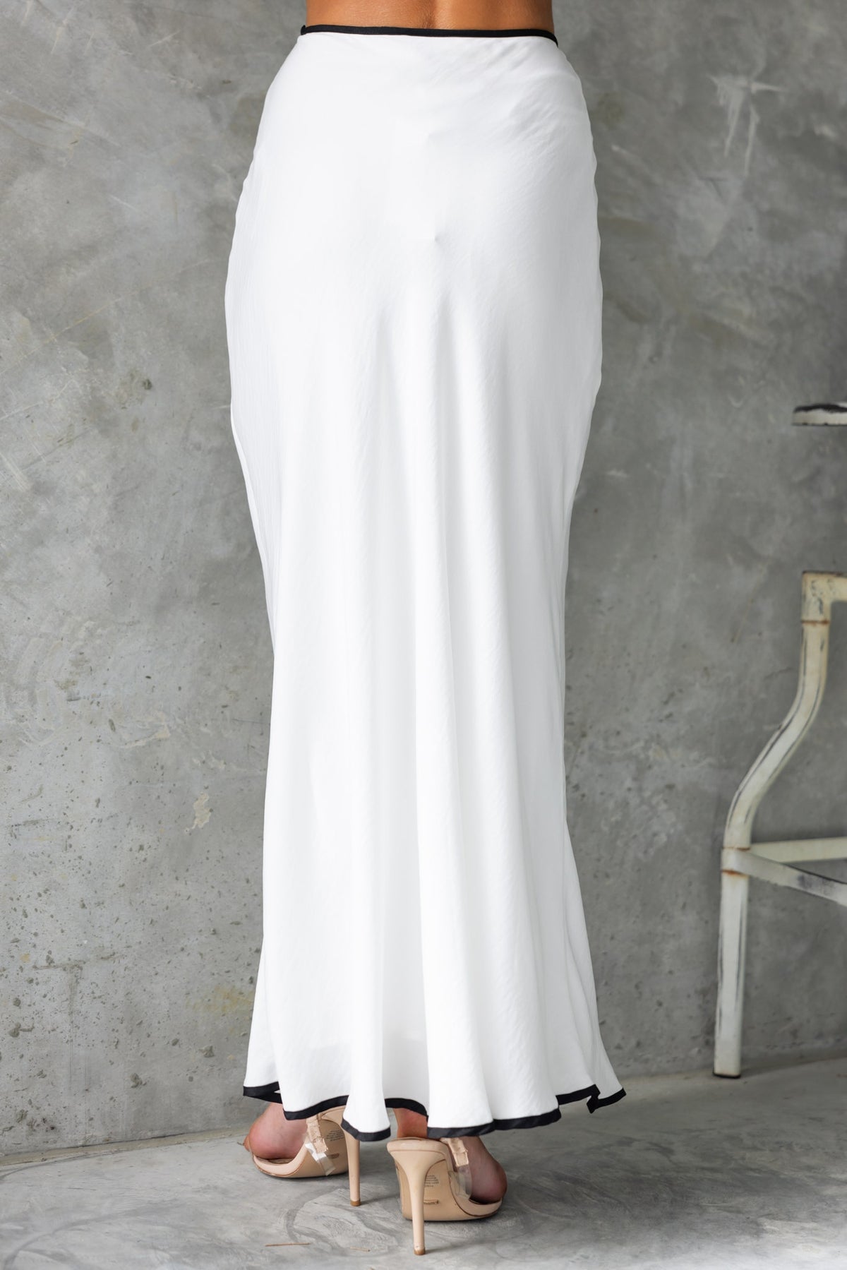 Virage Maxi Skirt in white with black trim, showcasing a mid-high waist fit and flowing design, perfect for elegant outings.
