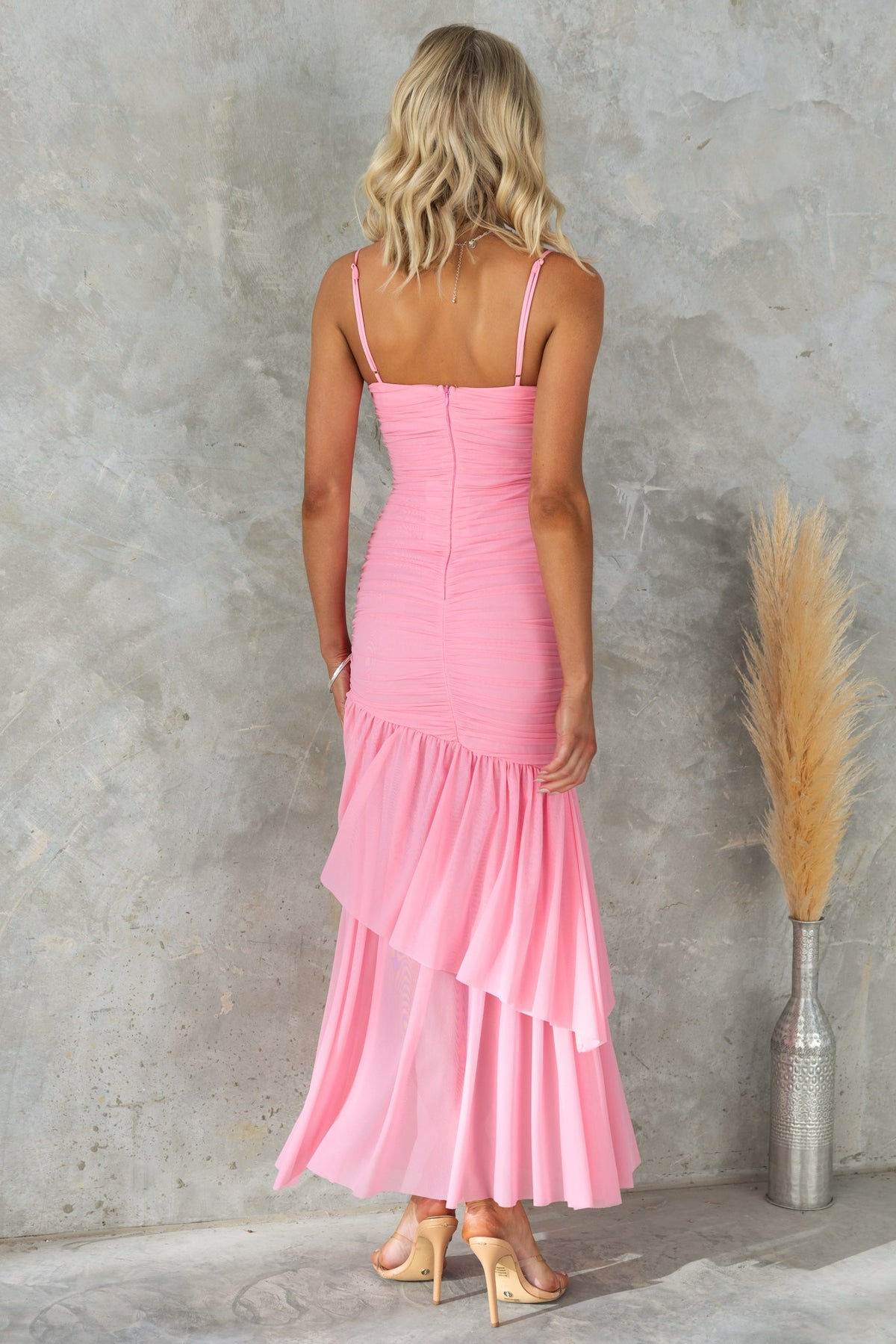 Back view of a pink Viante maxi dress with adjustable straps and layered ruffle hem, perfect for summer occasions.