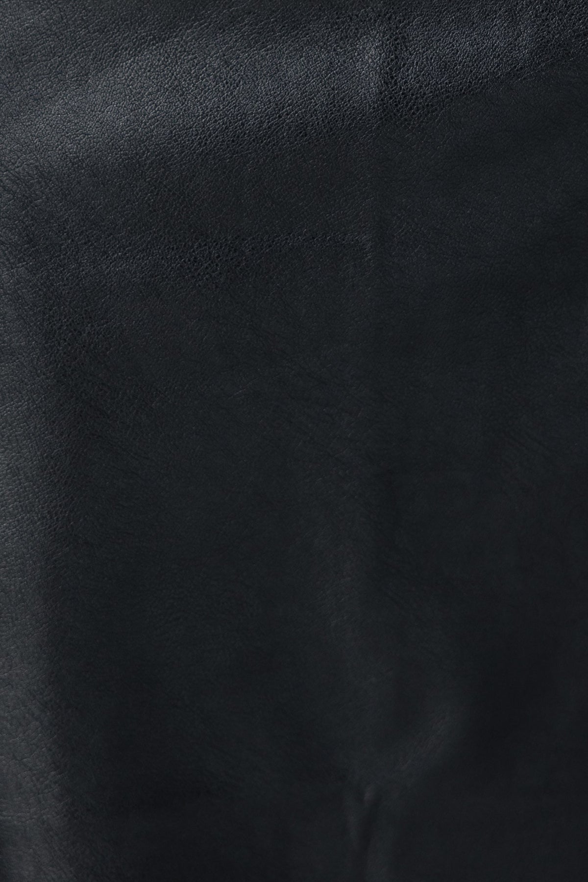 Close-up of black faux leather fabric, showcasing smooth texture for the Mayzie Midi Skirt, perfect for stylish outfits.