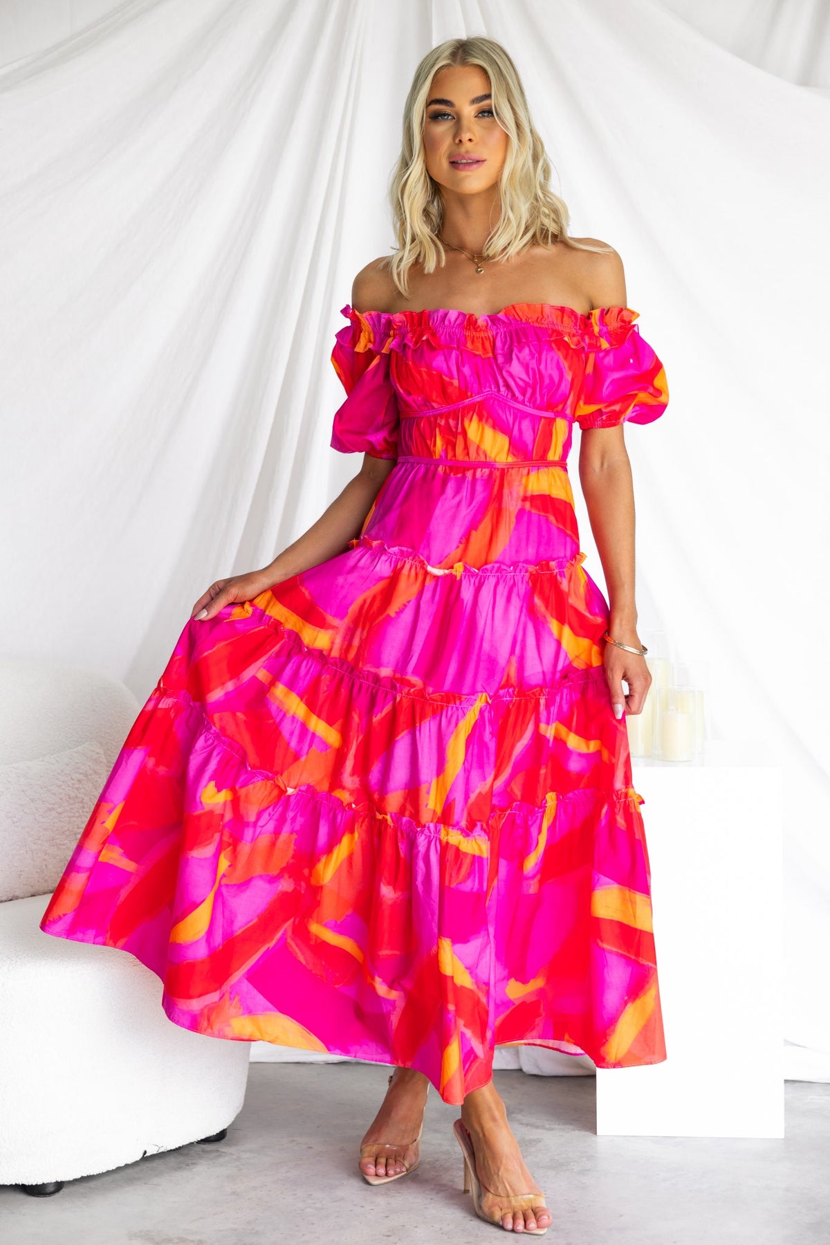 Model wearing a vibrant pink Archer Maxi Dress with off-shoulder neckline and tiered design, perfect for summer occasions.