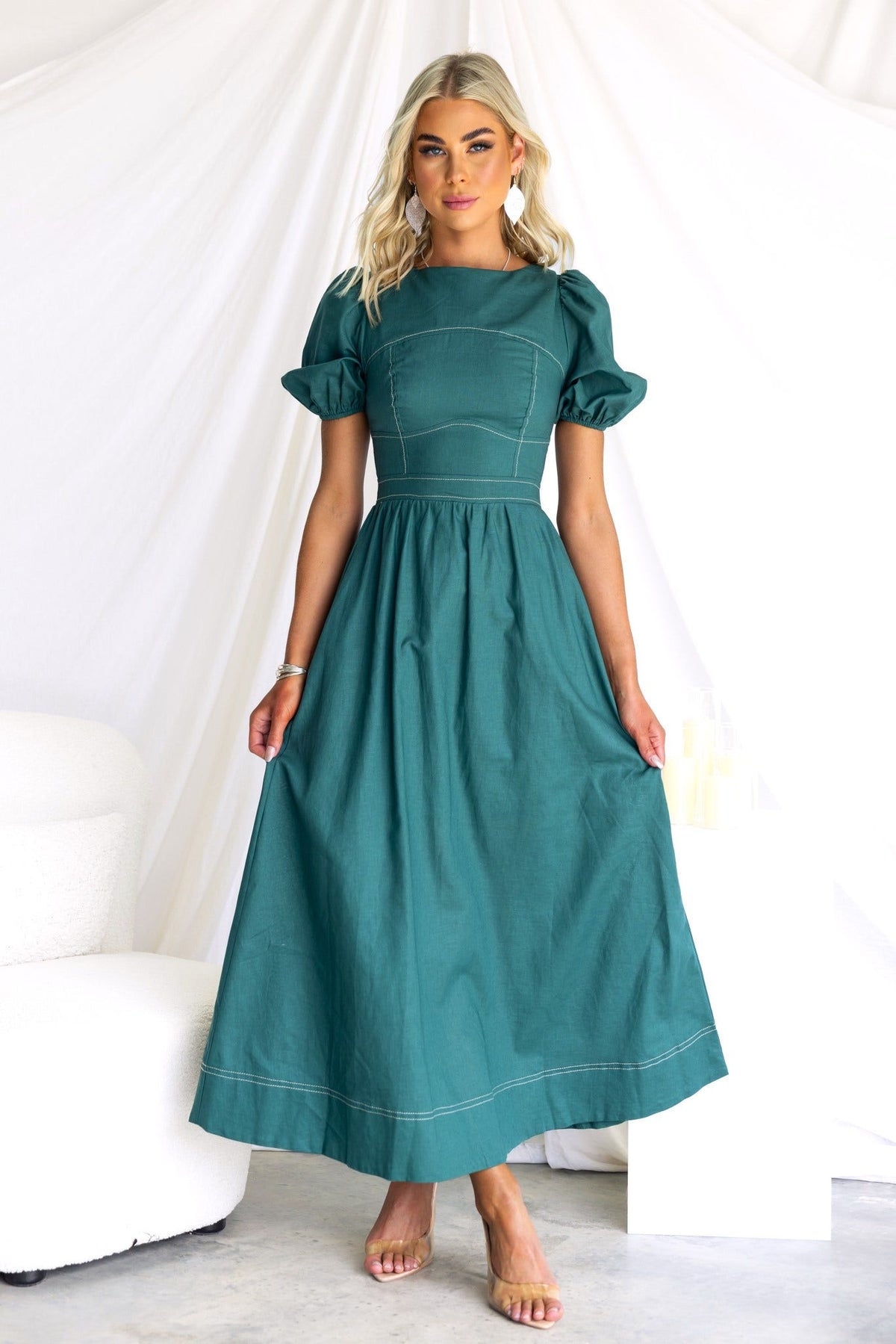 Model in a green Binita Maxi Dress with puffed sleeves and a fitted bodice, styled elegantly against a soft backdrop.