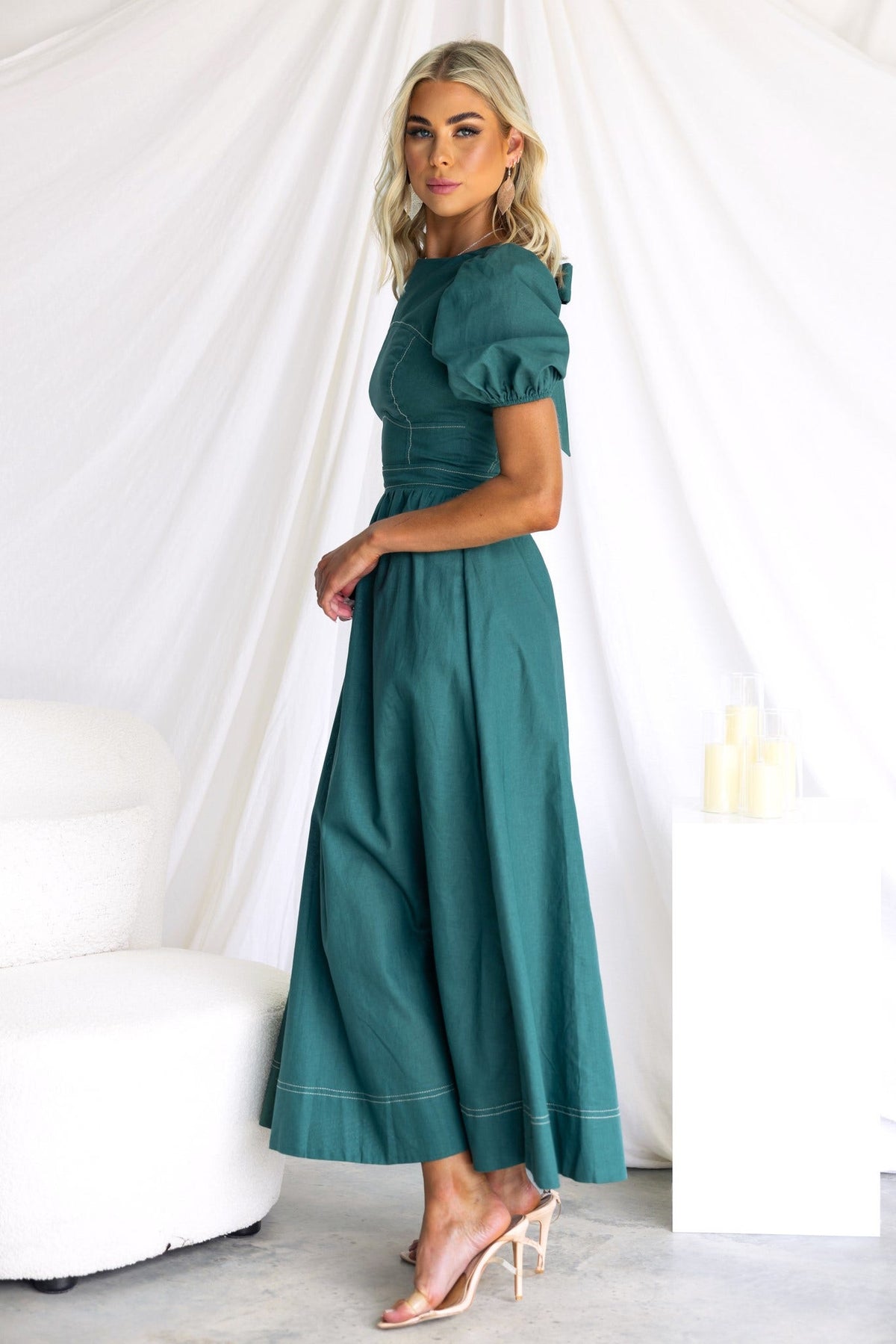 Elegant Binita Maxi Dress in teal with puff sleeves and a cinched waist, styled with clear heels.
