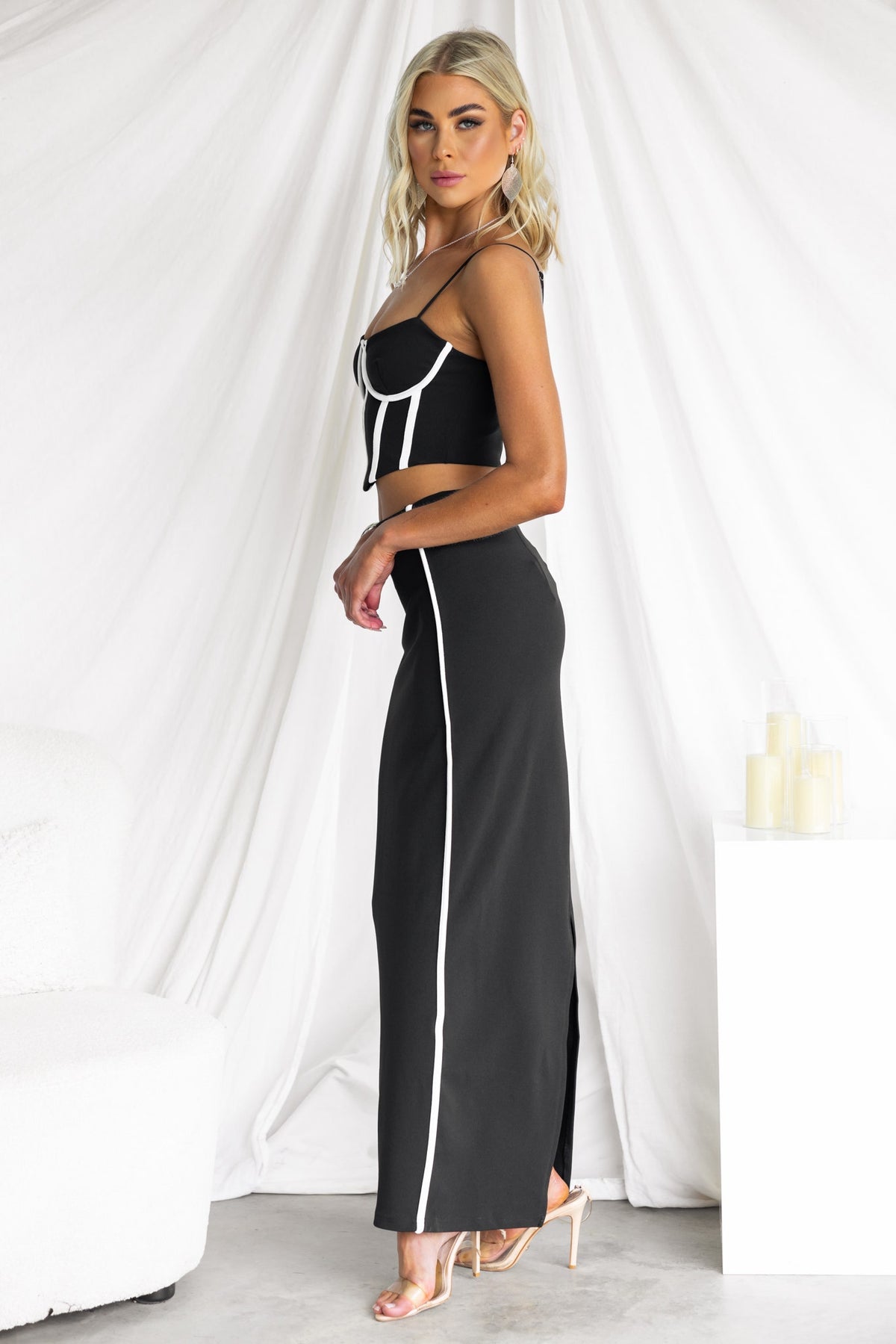 Model wearing the Above And Beyond Set, a black maxi skirt and top with adjustable straps and a side split.