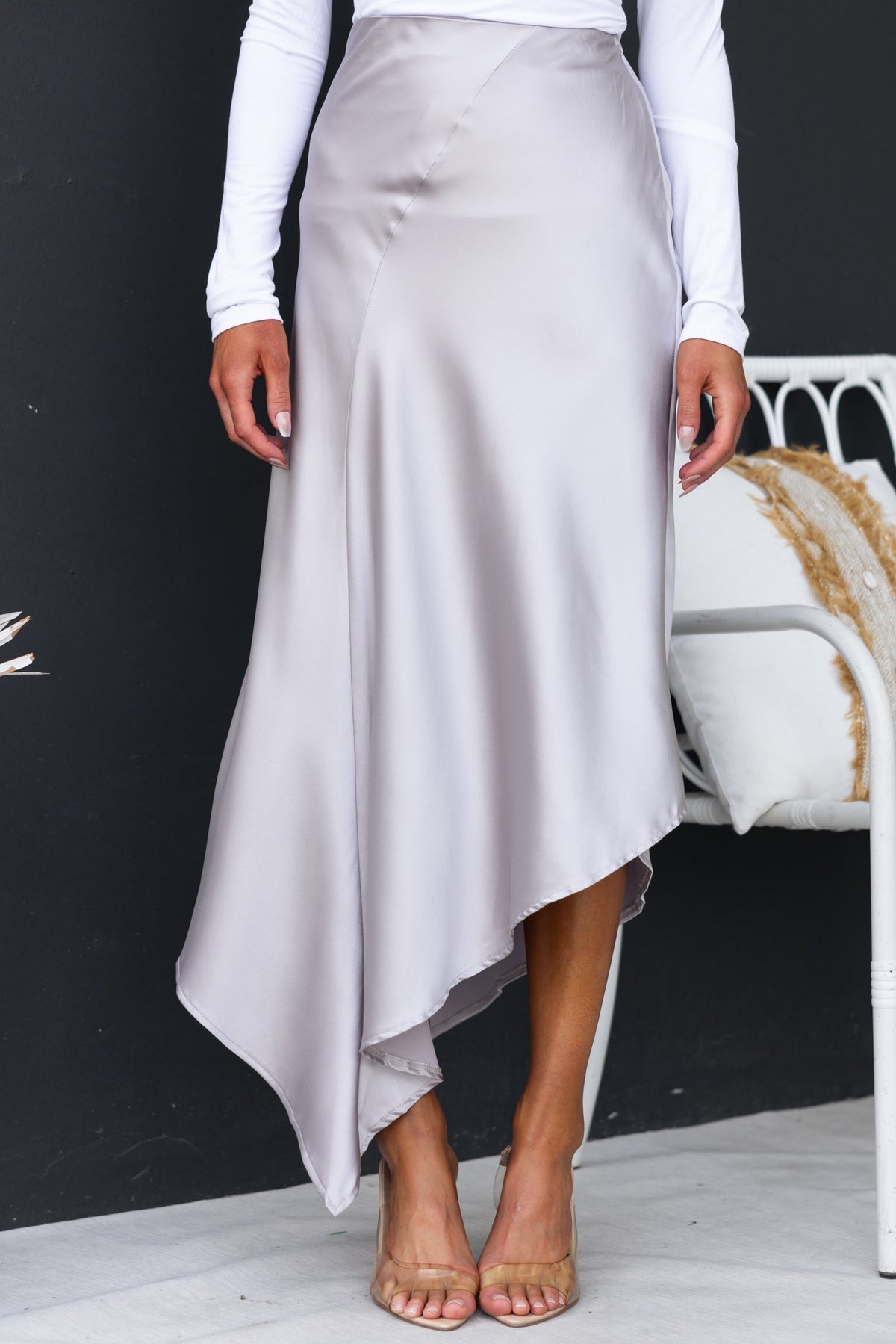 Giallo midi skirt in satin finish featuring an asymmetric hemline, high waist, and elastic waistband, styled for a chic look.