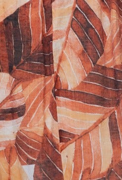 Close-up of Damaris Maxi Dress fabric featuring vibrant orange and brown leaf patterns on lightweight chiffon material.