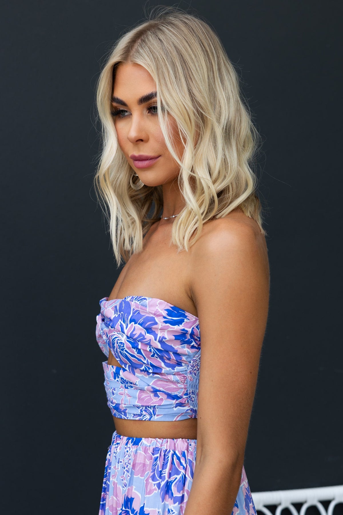 Model wearing an enchanting strapless top with floral print and twist detail, showcasing elegant summer style.
