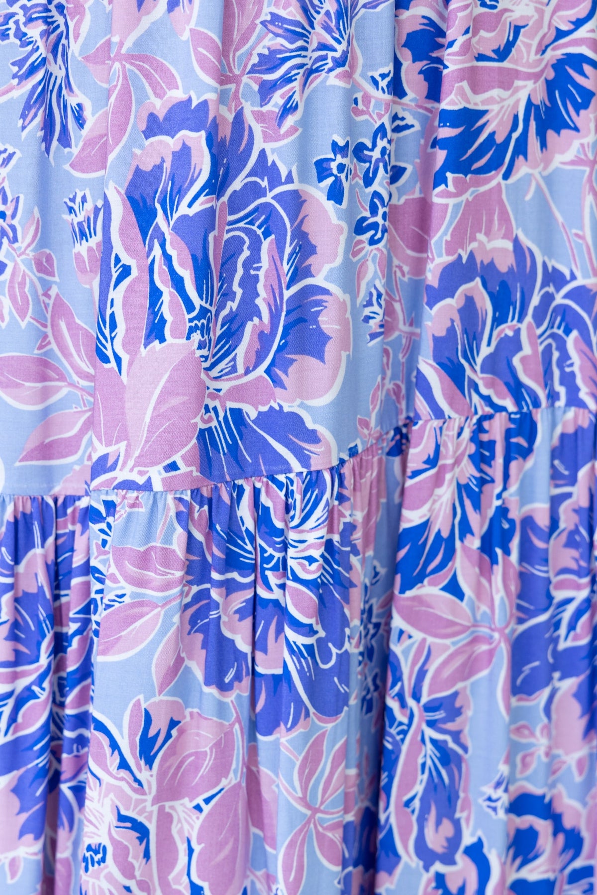 Close-up of floral fabric in shades of blue and pink, showcasing a beautiful design for an enchanting top.