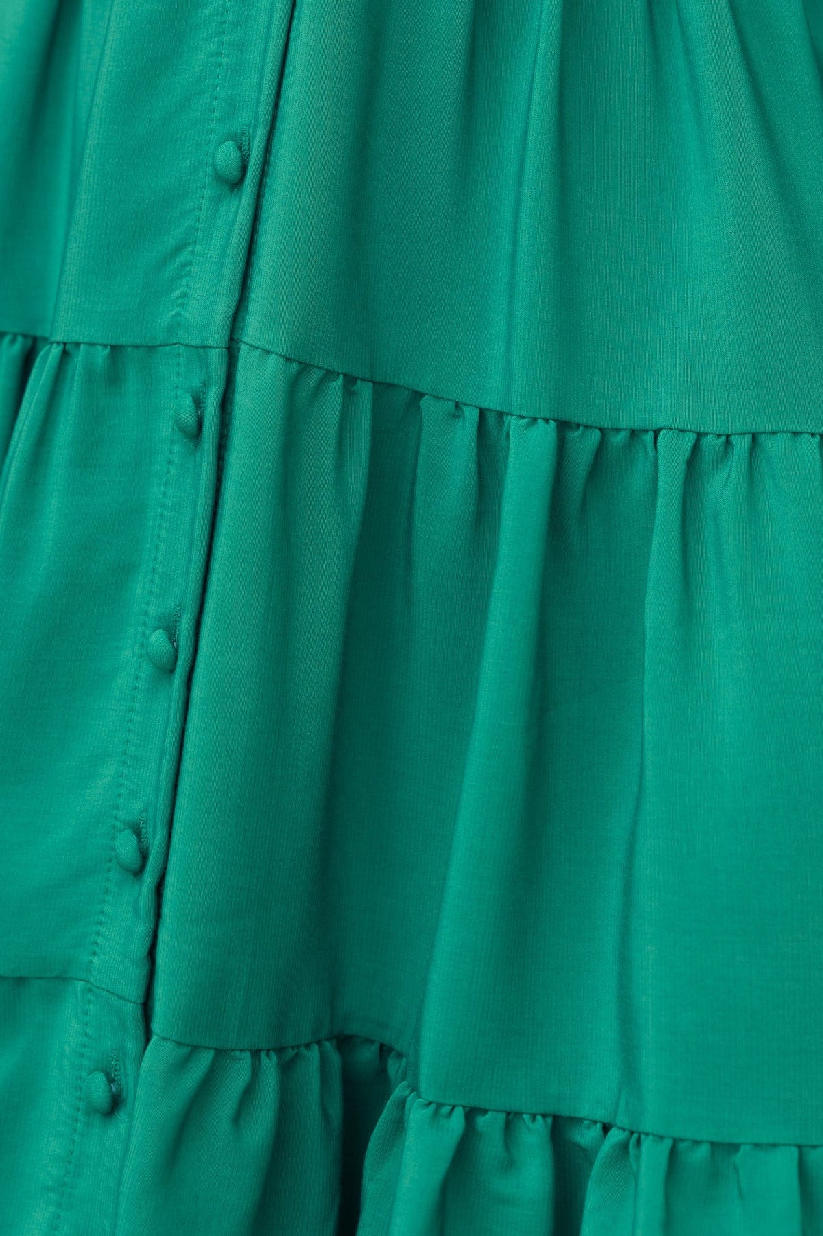 Close-up of Damika Dress in vibrant green chiffon with button-up front and tiered ruffle design.
