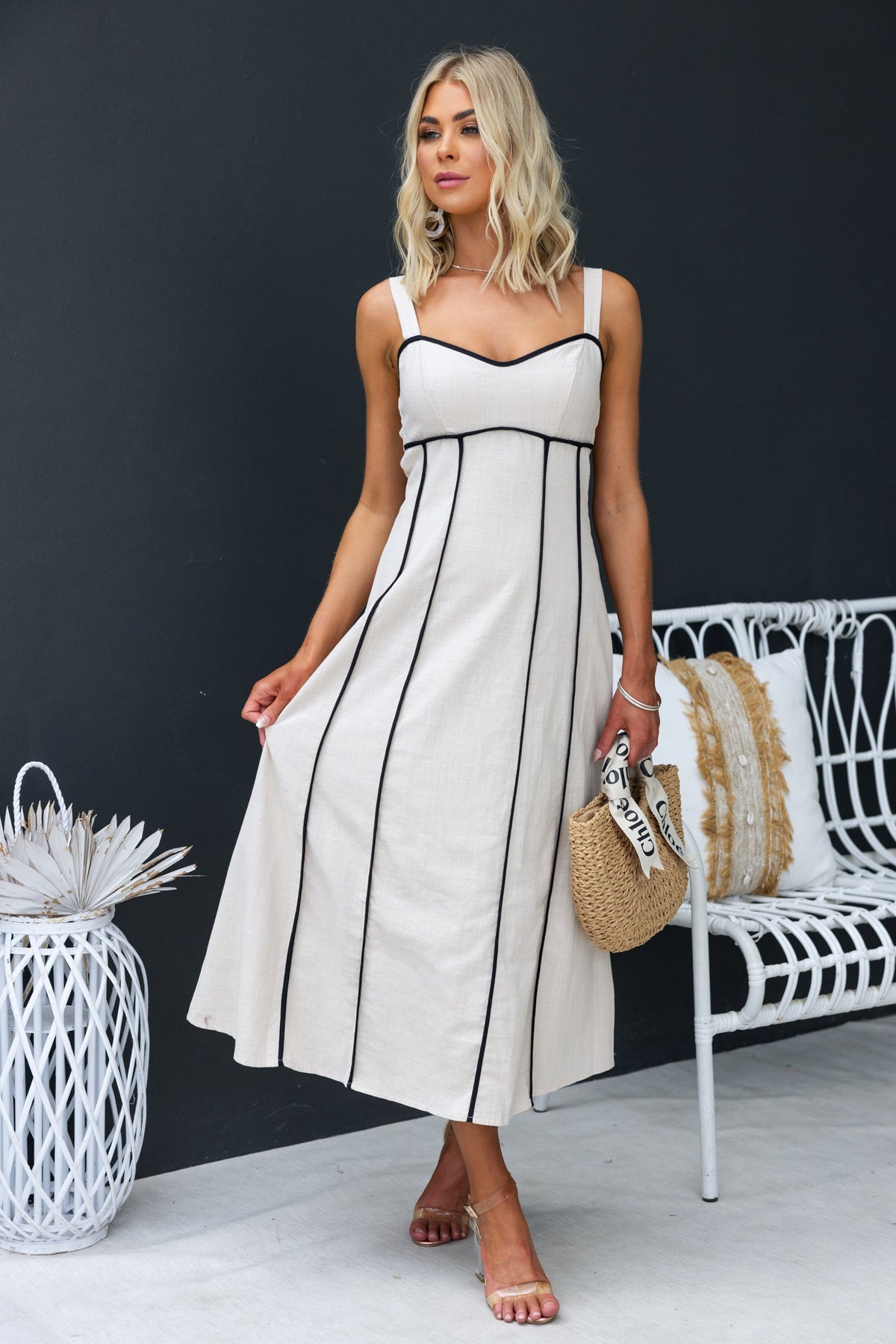 Temila Midi Dress featuring adjustable straps, linen texture, and elegant design, styled with accessories in a modern setting.