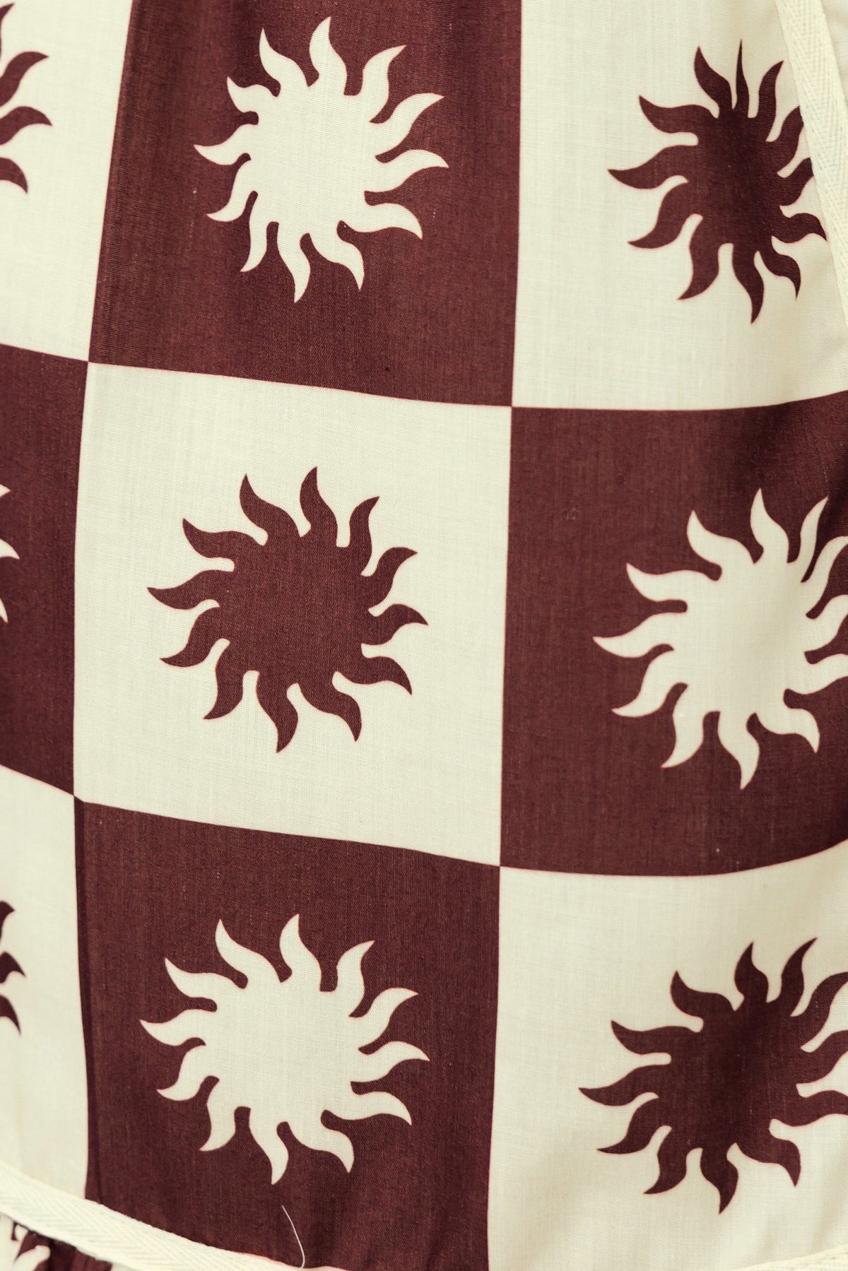 Close-up of Cianna Midi Dress fabric featuring sun pattern in burgundy and cream.