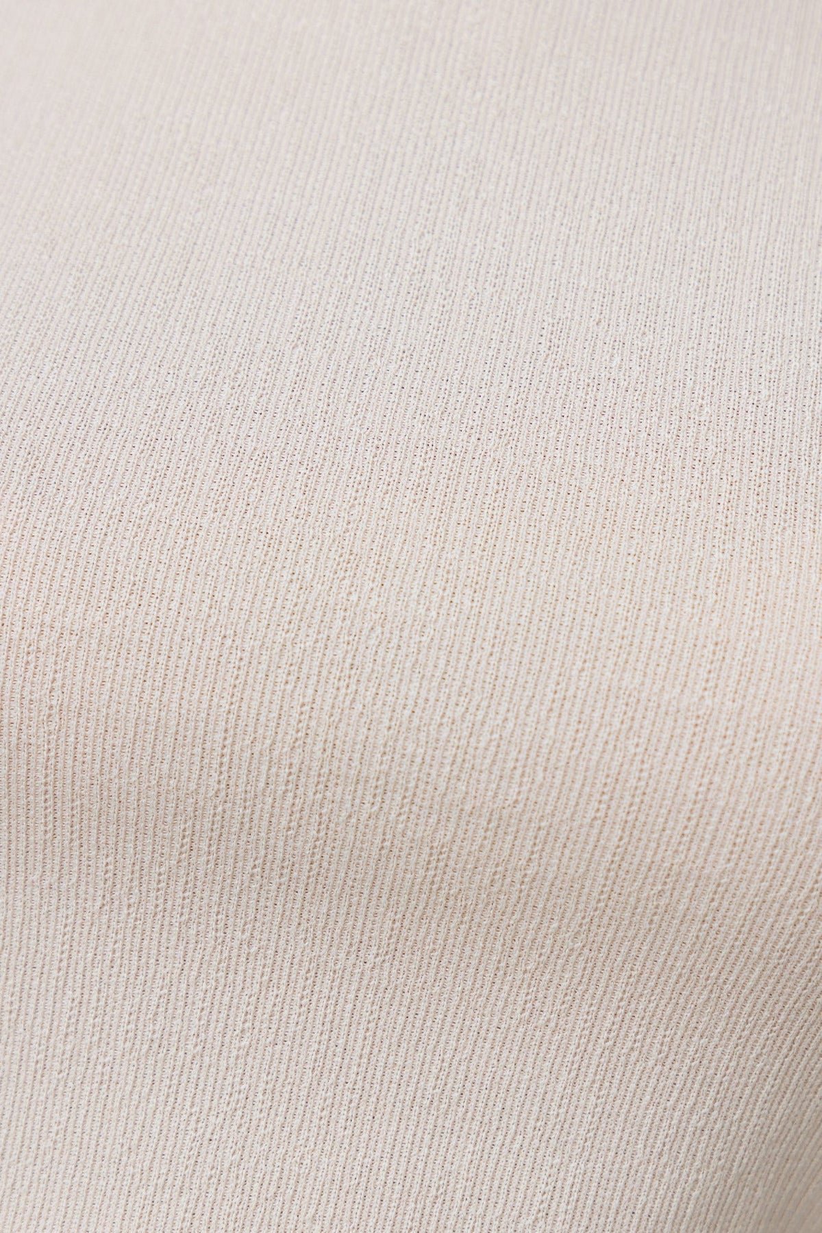 Close-up of textured beige fabric showcasing stretch material for versatile clothing designs.