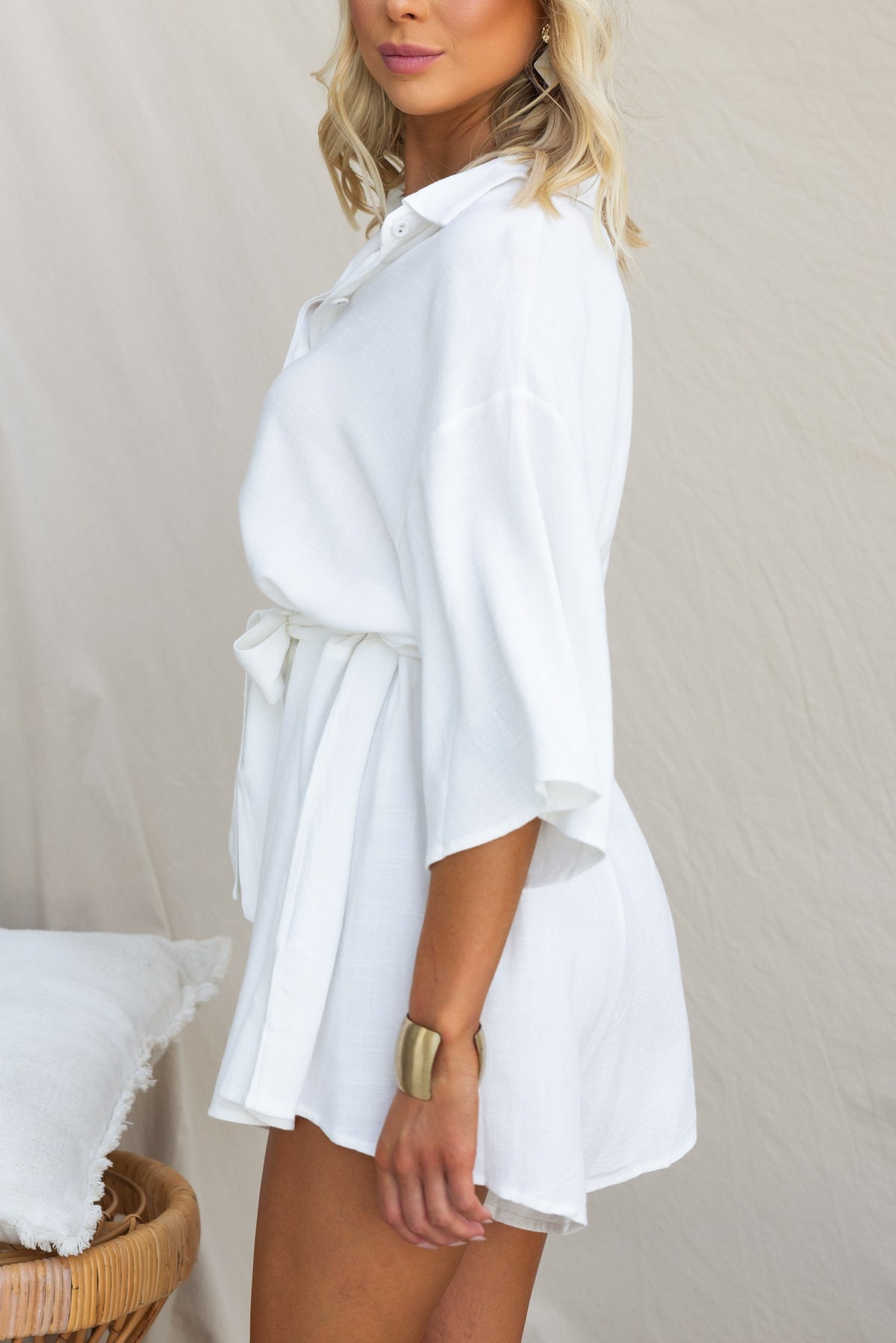 Model wearing the Wyoma Playsuit, a white linen blend outfit with a collar and removable tie, showcasing a relaxed fit.