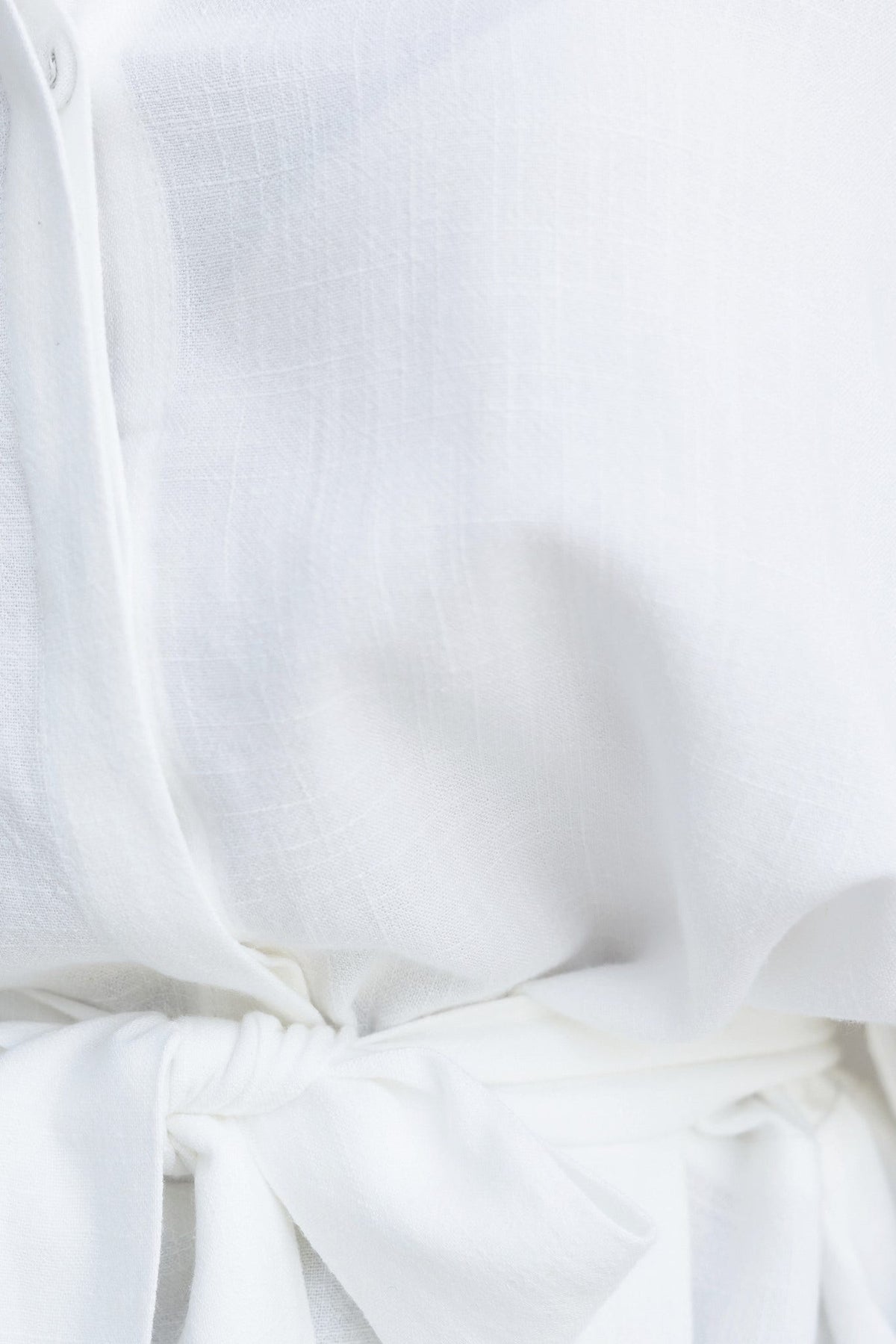 Close-up of the Wyoma Playsuit showing soft white linen fabric and a tied waist detail for a relaxed fit.