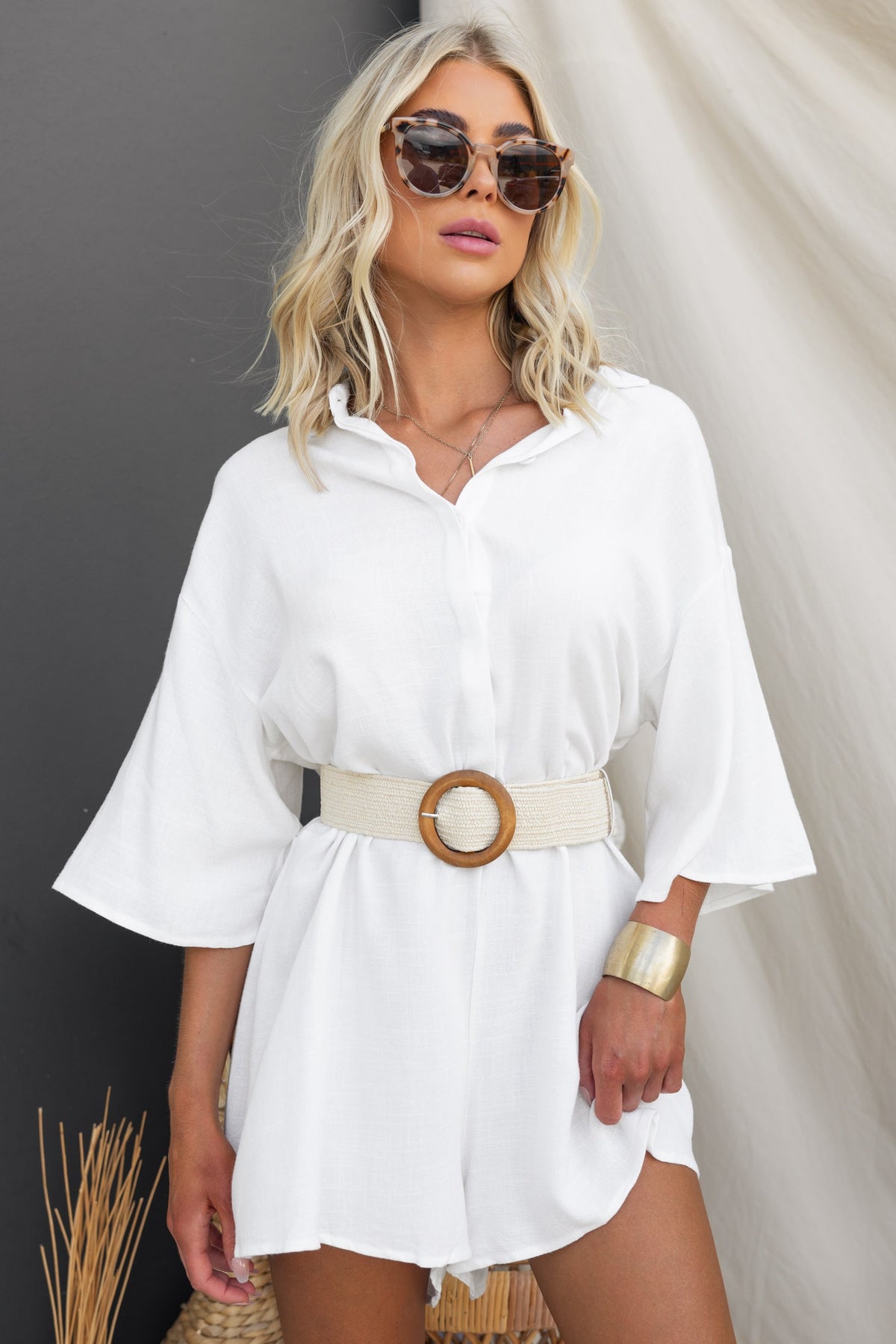 Model wearing a white shirt dress styled with a Cancun Belt featuring a wooden buckle, sunglasses, and a chic look.
