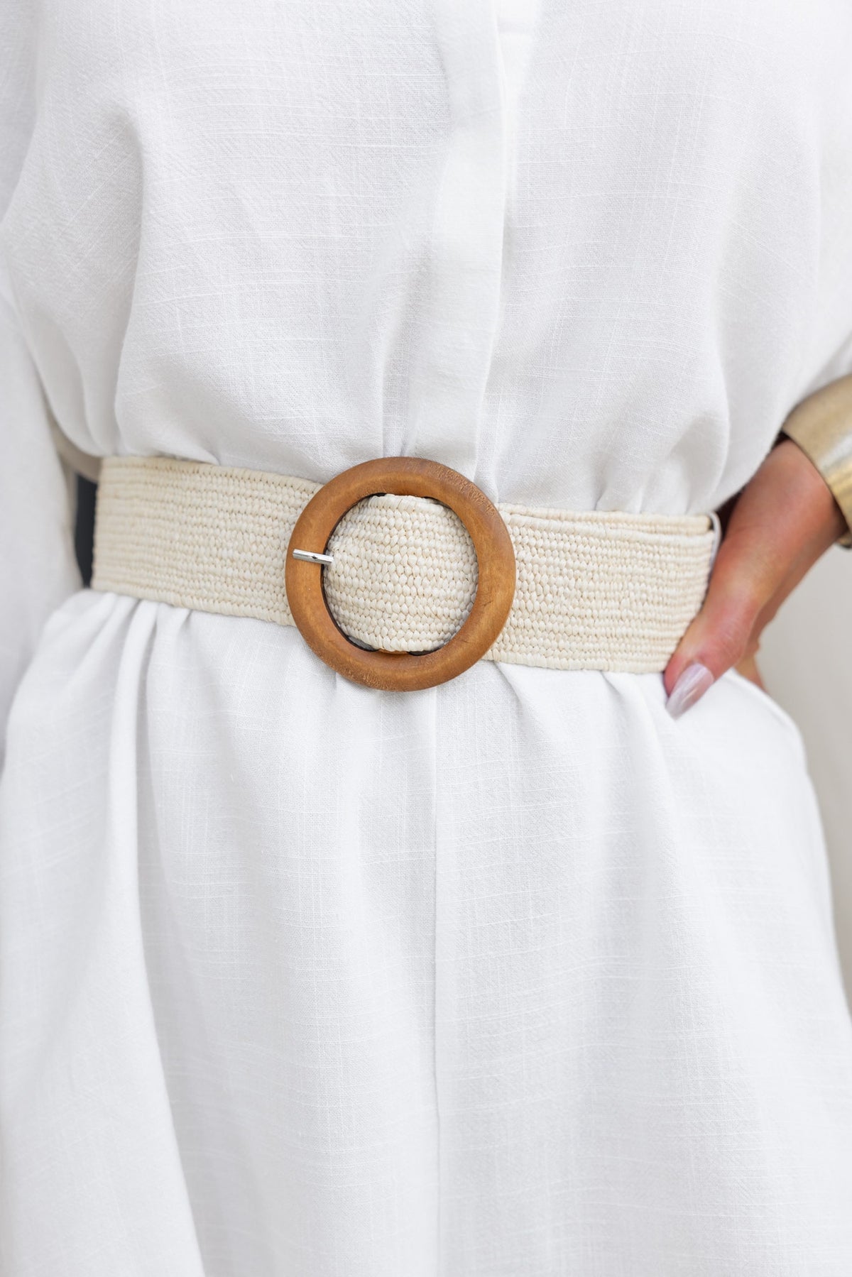 Elegant Cancun Belt with wooden buckle, made from stretch material, styled on a model wearing a white outfit.