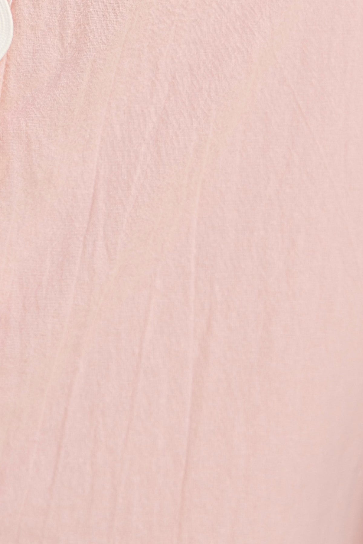 Close-up of Alfonzo Dress in soft pink fabric, showcasing the texture and button detail.