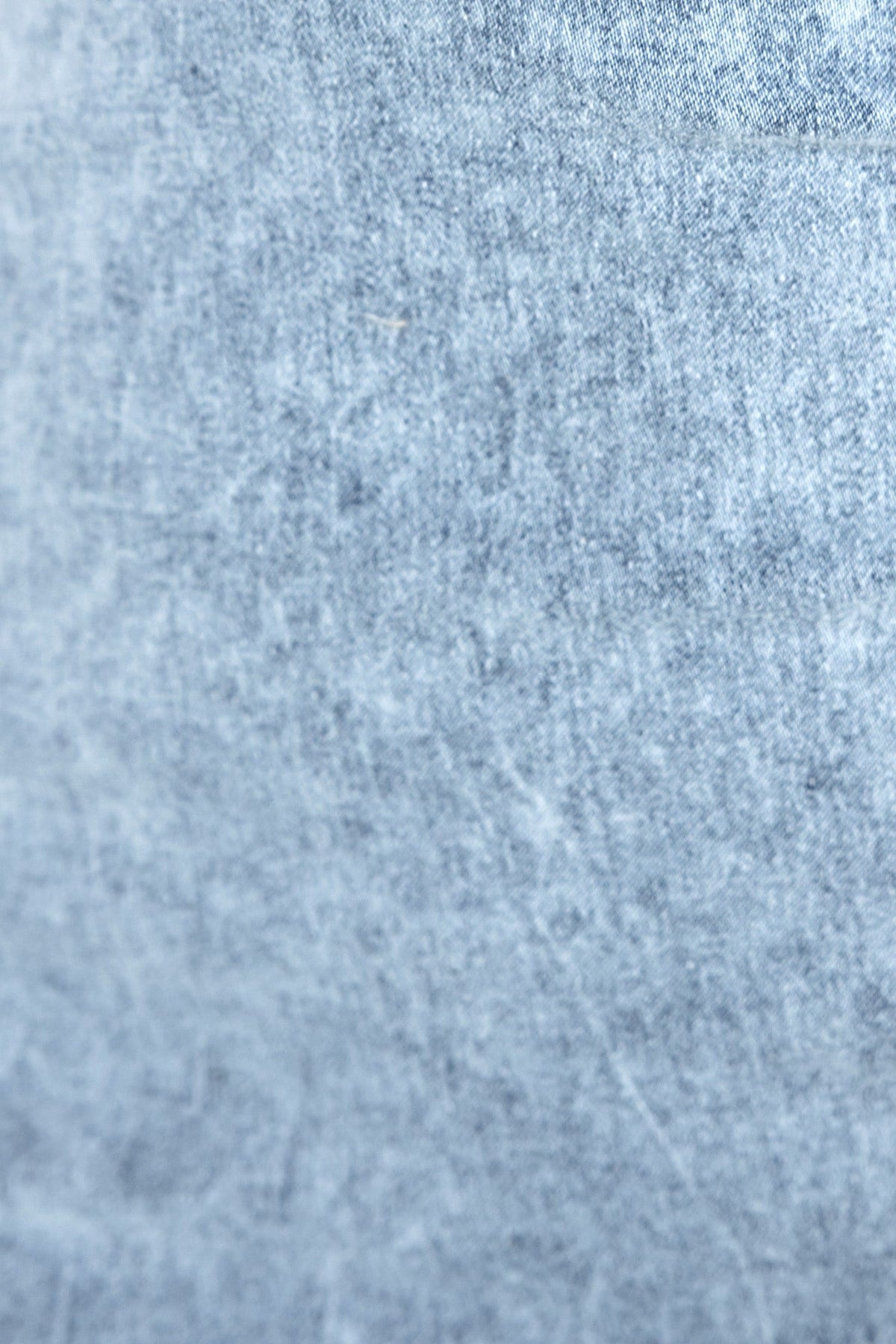 Close-up of soft denim fabric texture, showcasing a light blue hue, perfect for a stylish denim dress.