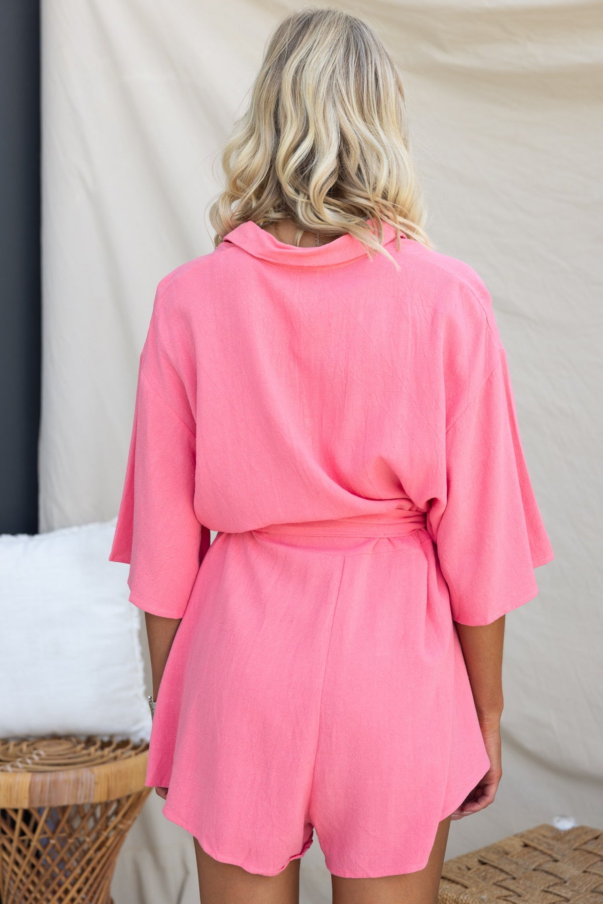 Back view of a woman in a pink Wyoma playsuit, featuring a relaxed fit, collar, and removable tie.