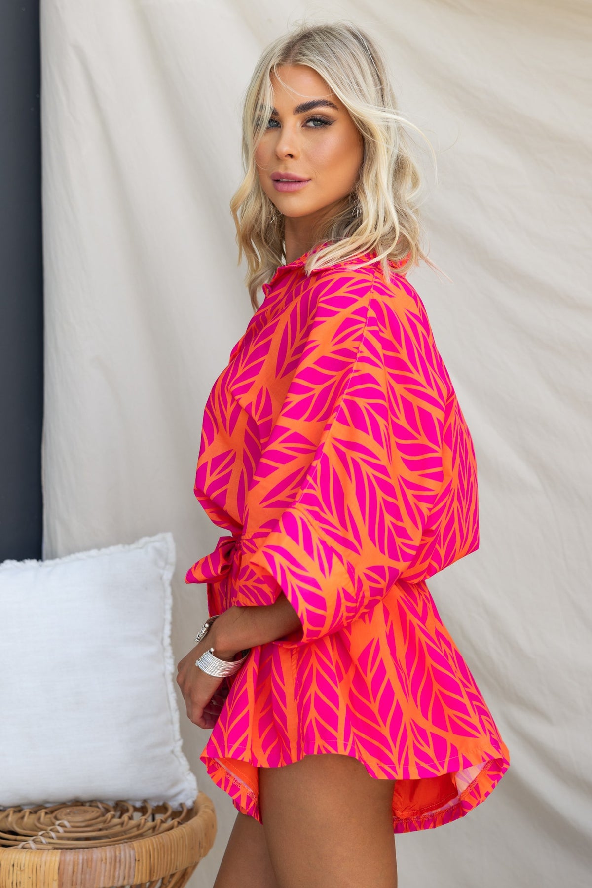 Model wearing a bright pink and orange Hollis Playsuit with leaf pattern, showcasing the relaxed fit and button-up design.