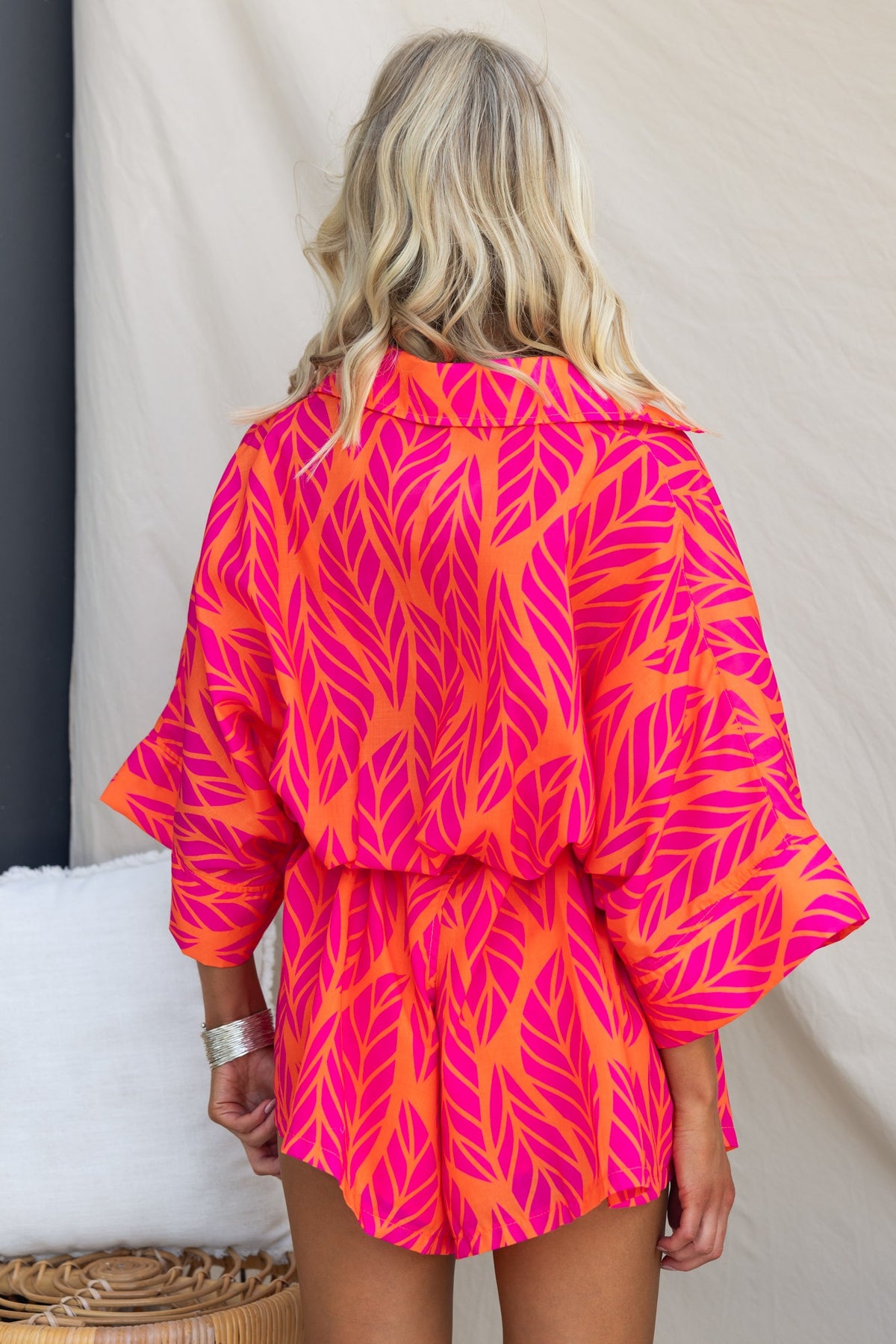 Model wearing the vibrant pink Hollis Playsuit with leaf design, showcasing the back view and relaxed fit.