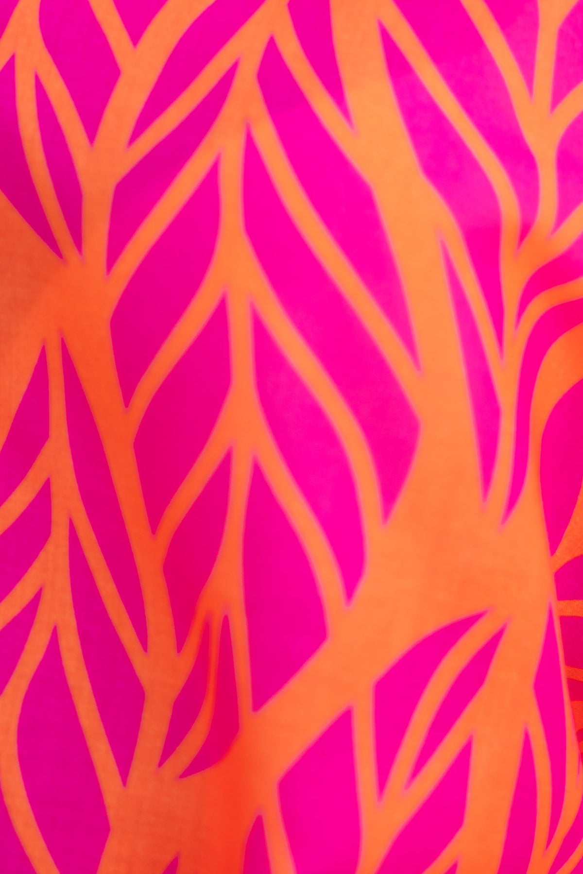 Vibrant pink and orange fabric with a leaf-like pattern, perfect for stylish summer attire.