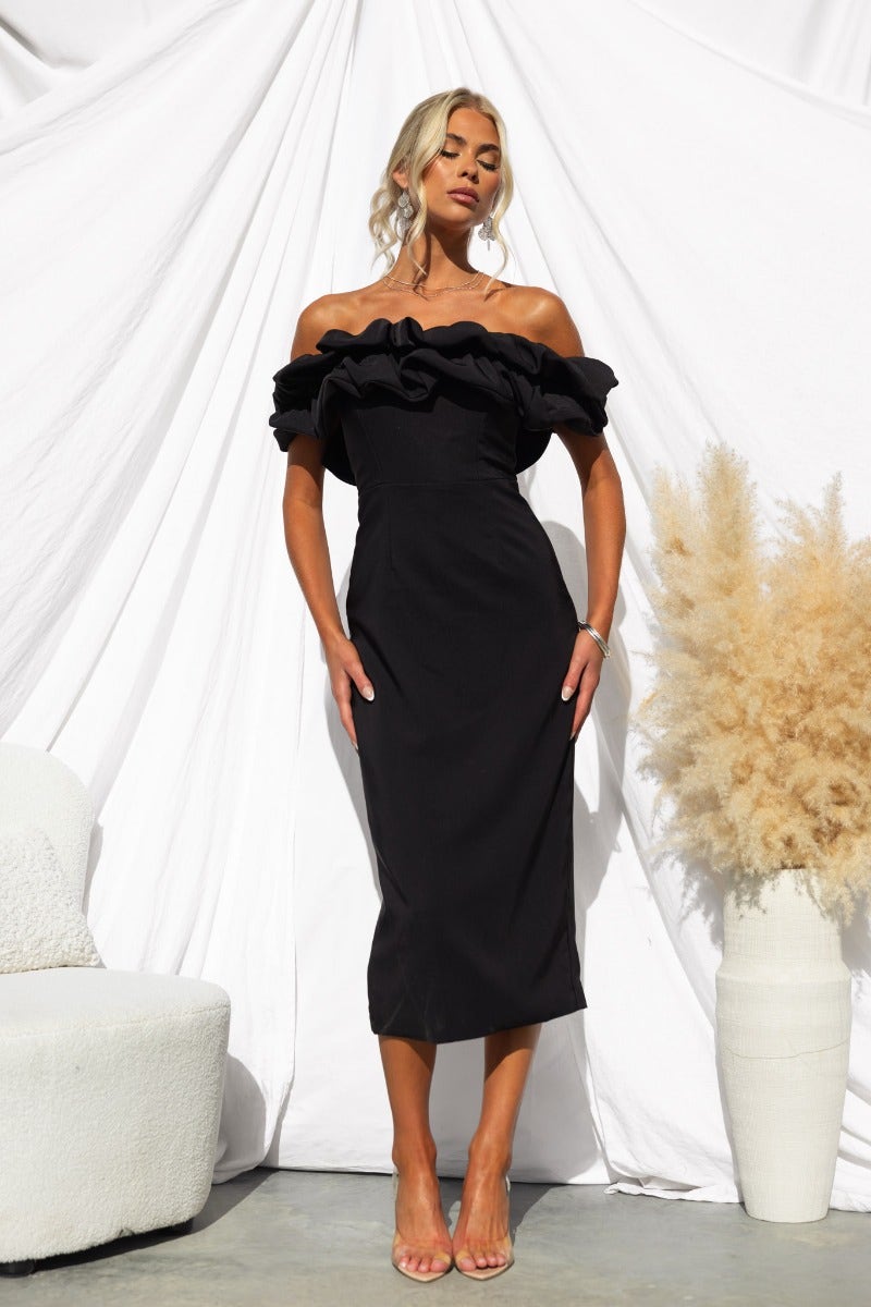 Black off-shoulder midi dress with ruffle detailing, slim fit, and elegant back split, styled for a chic look.